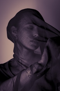 Woman covered with sheer fabric, eyes closed.