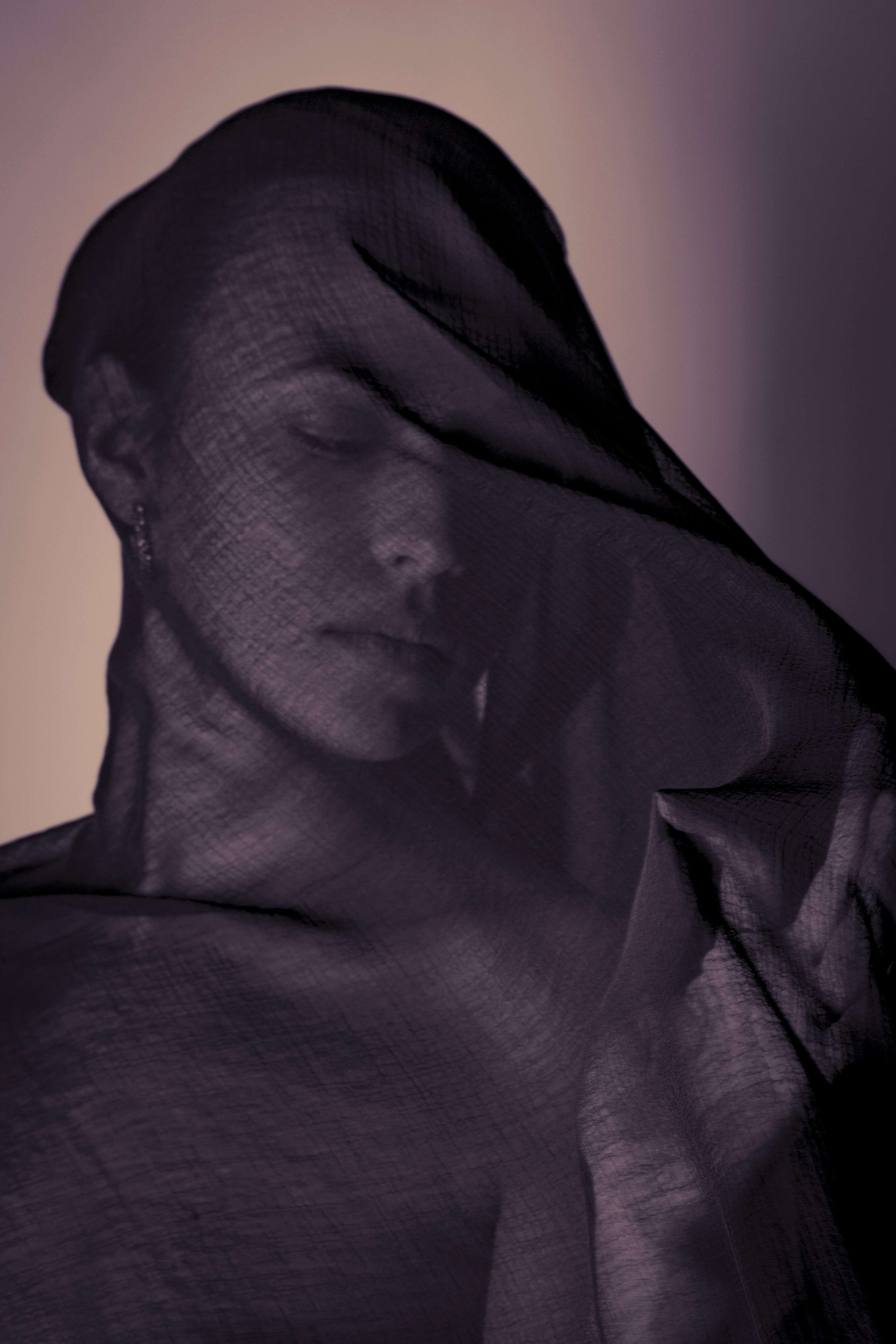 Woman's face covered by dark sheer fabric
