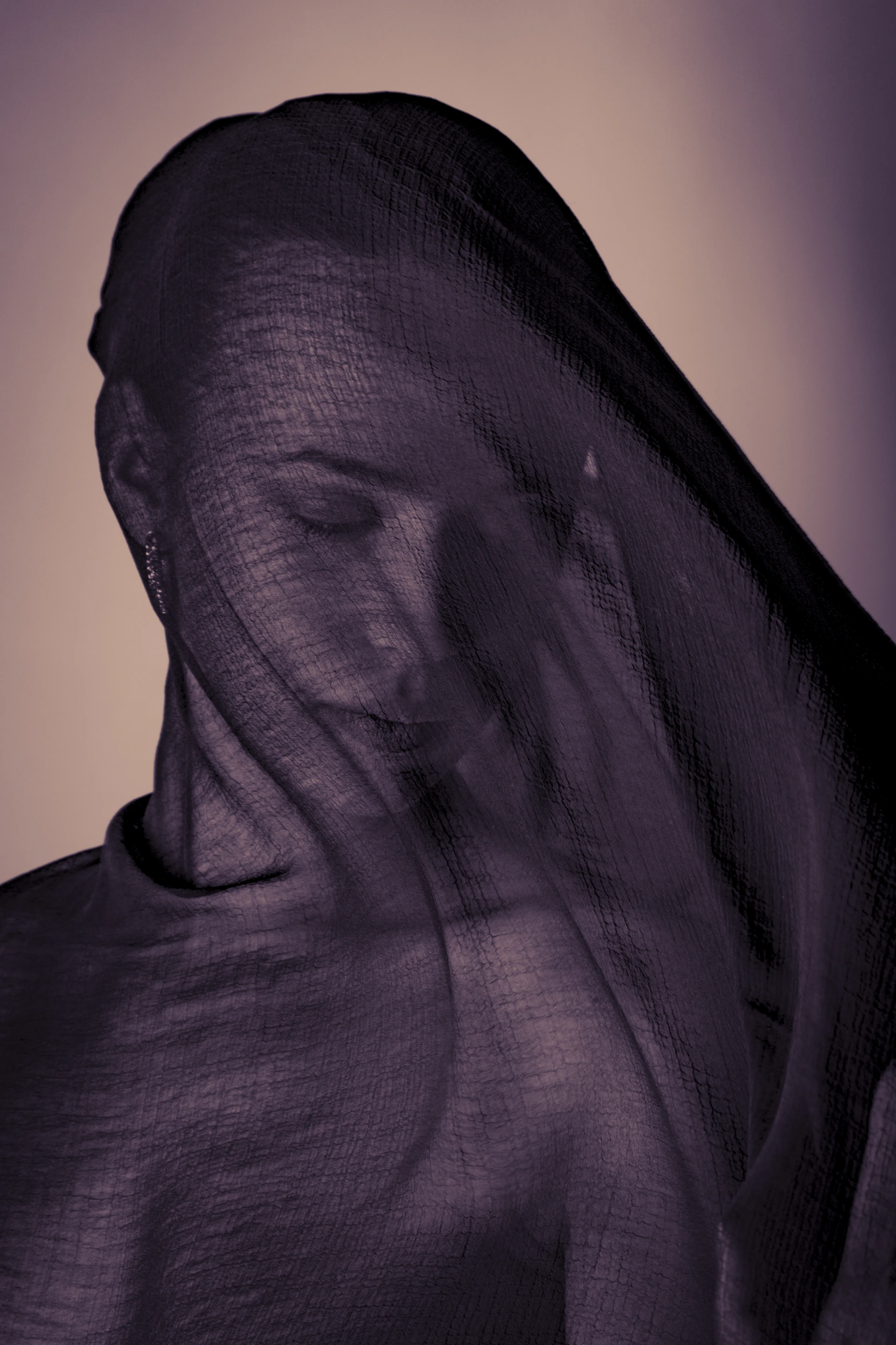 Woman's face covered with sheer purple fabric
