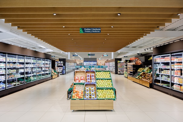 A well-lit grocery store aisle with produce displays.