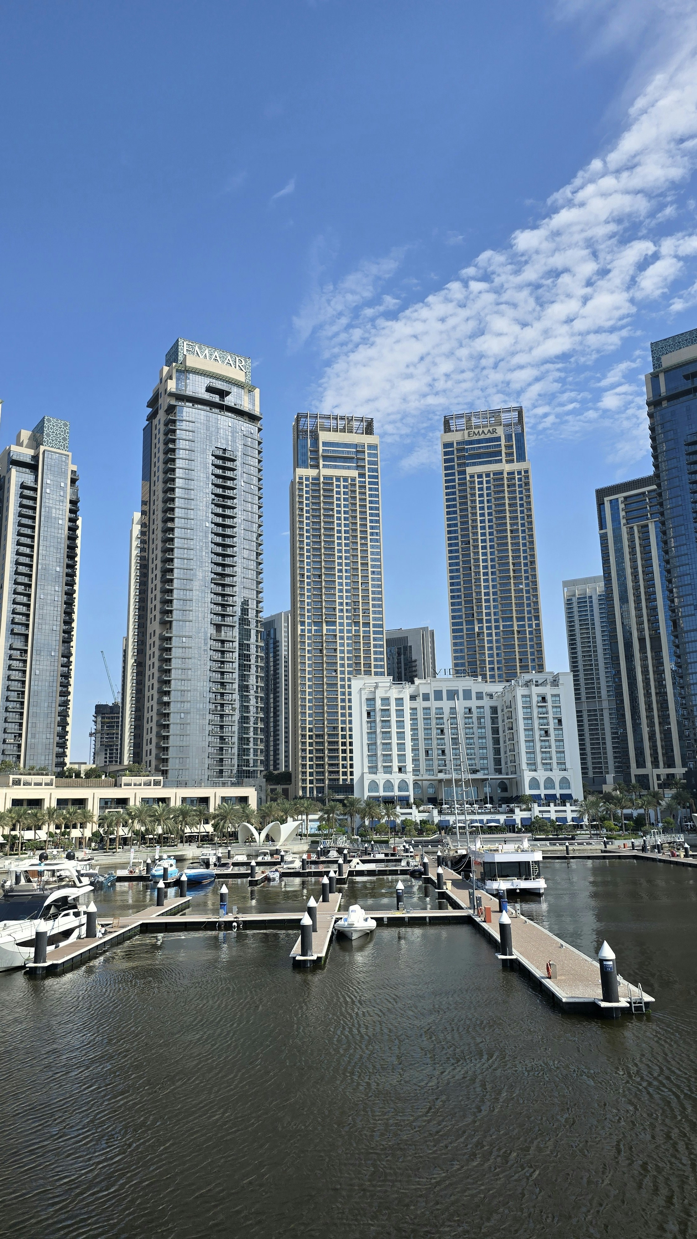 Arranha-céus modernos têm vista para uma marina com barcos na água.