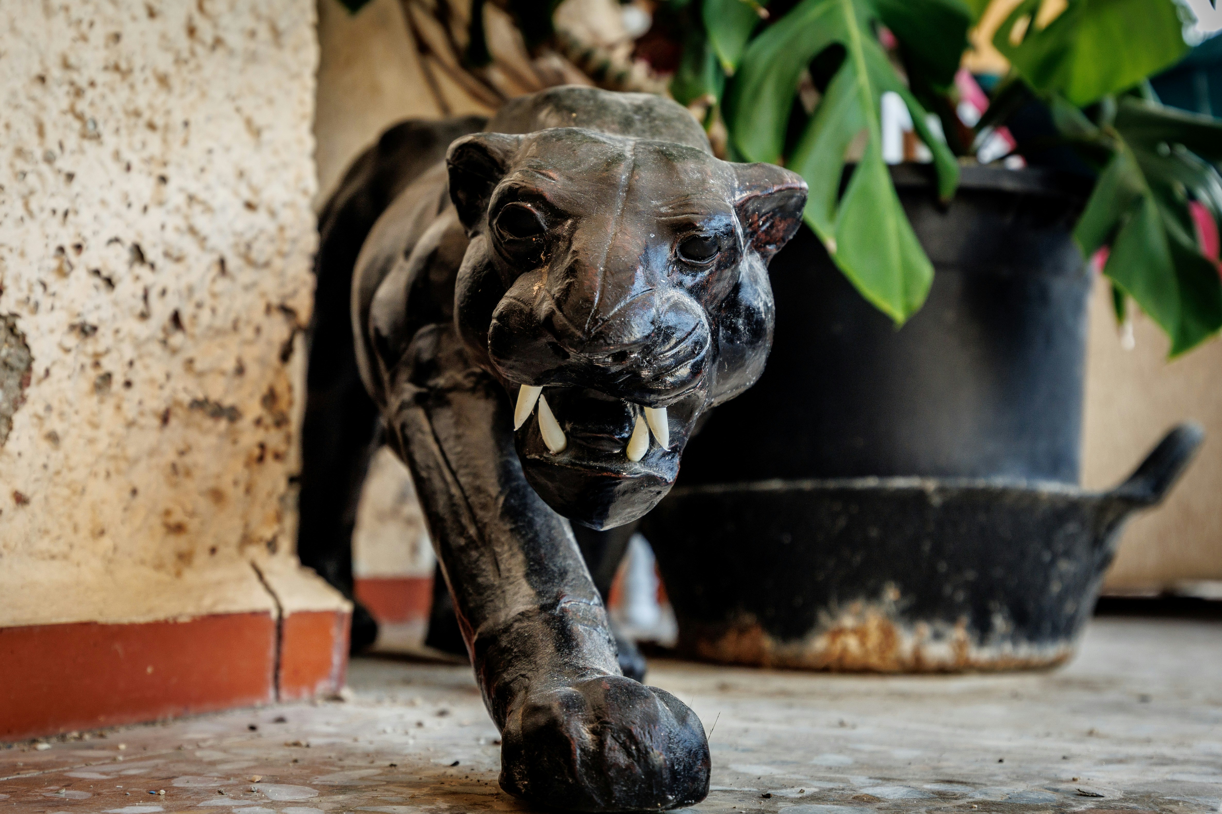 Uma escultura de madeira de uma pantera negra andando para a frente.