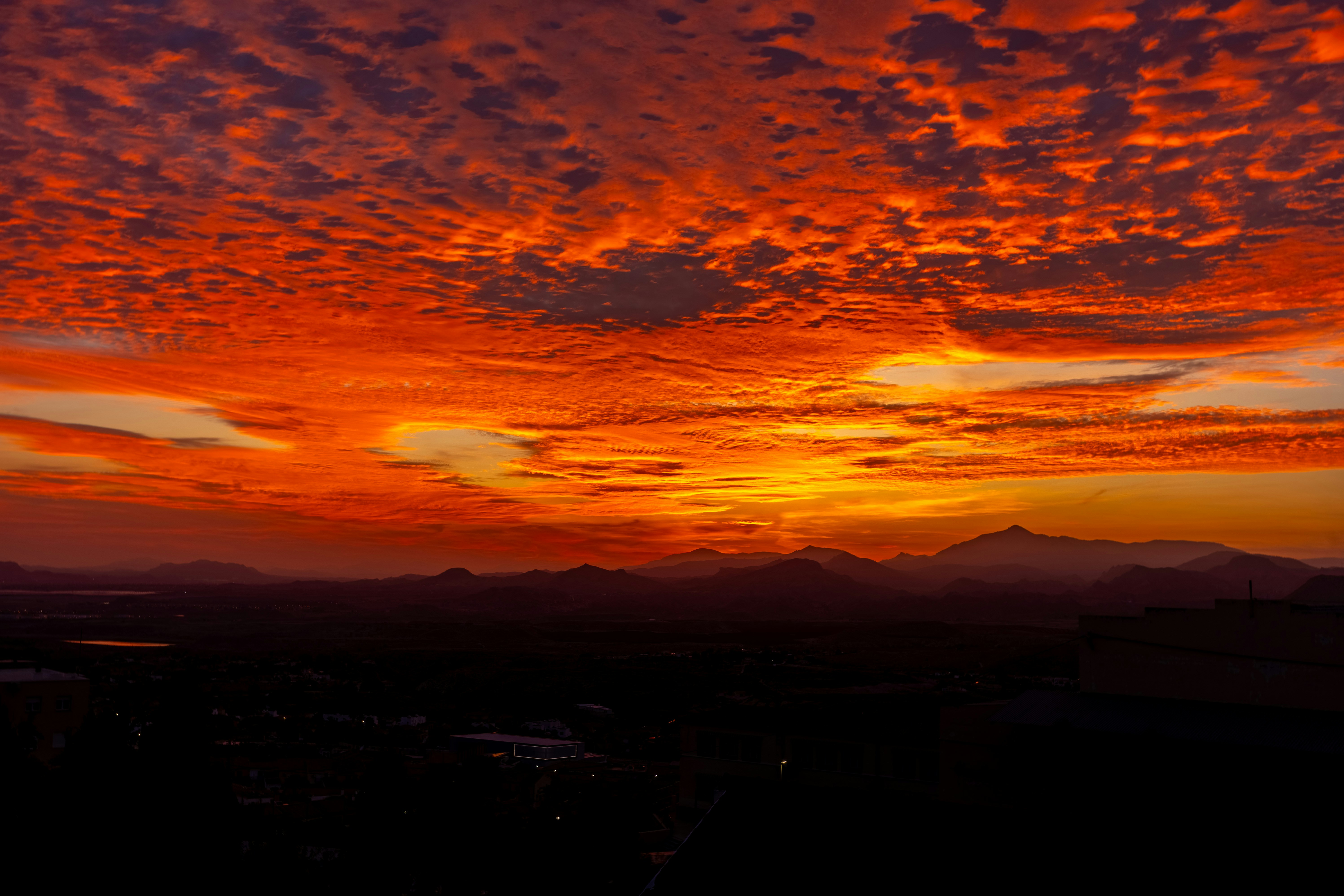 Nuvens ardentes do pôr do sol sobre montanhas distantes ao anoitecer