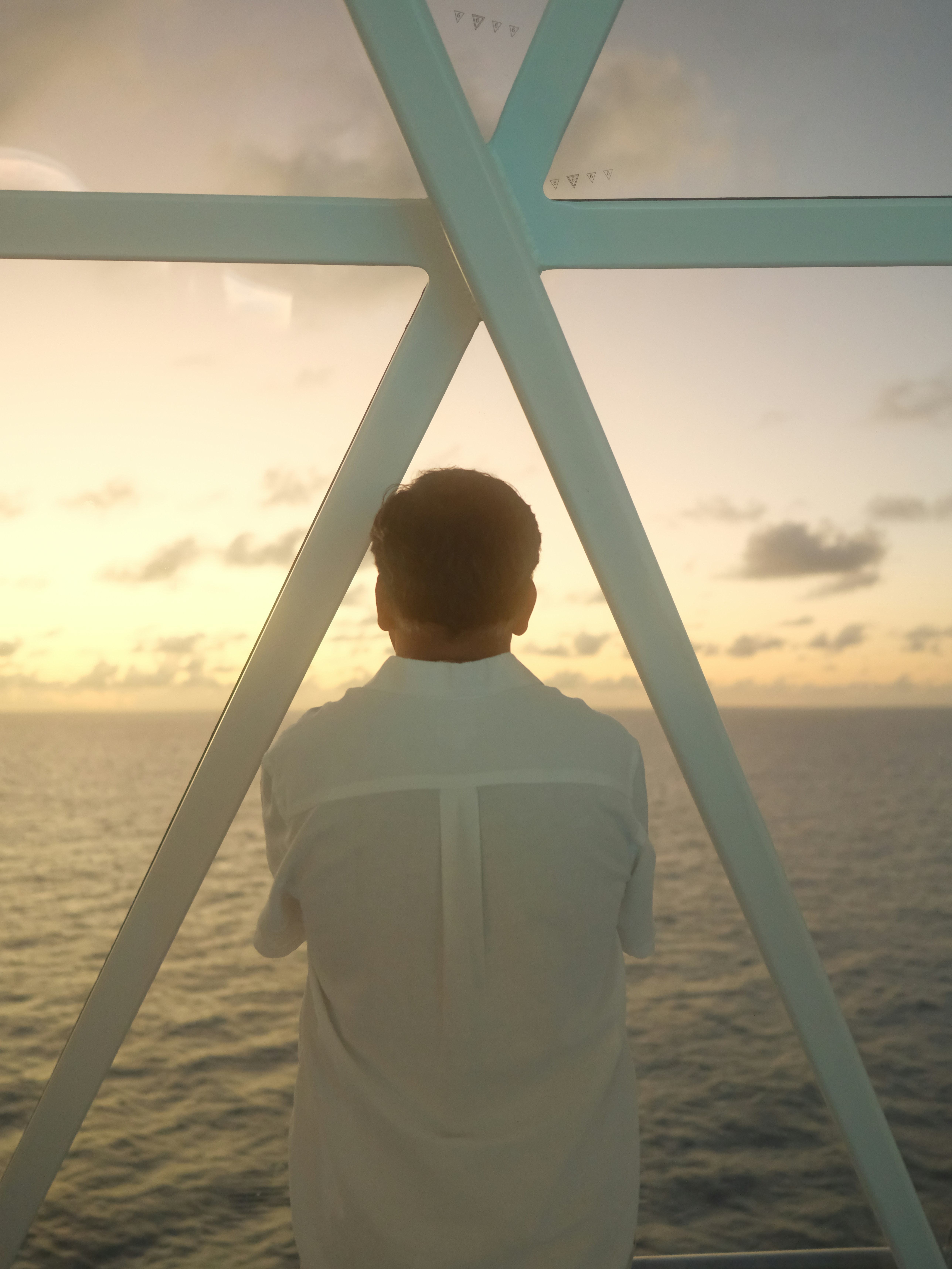 Man in white shirt watching sunset over ocean