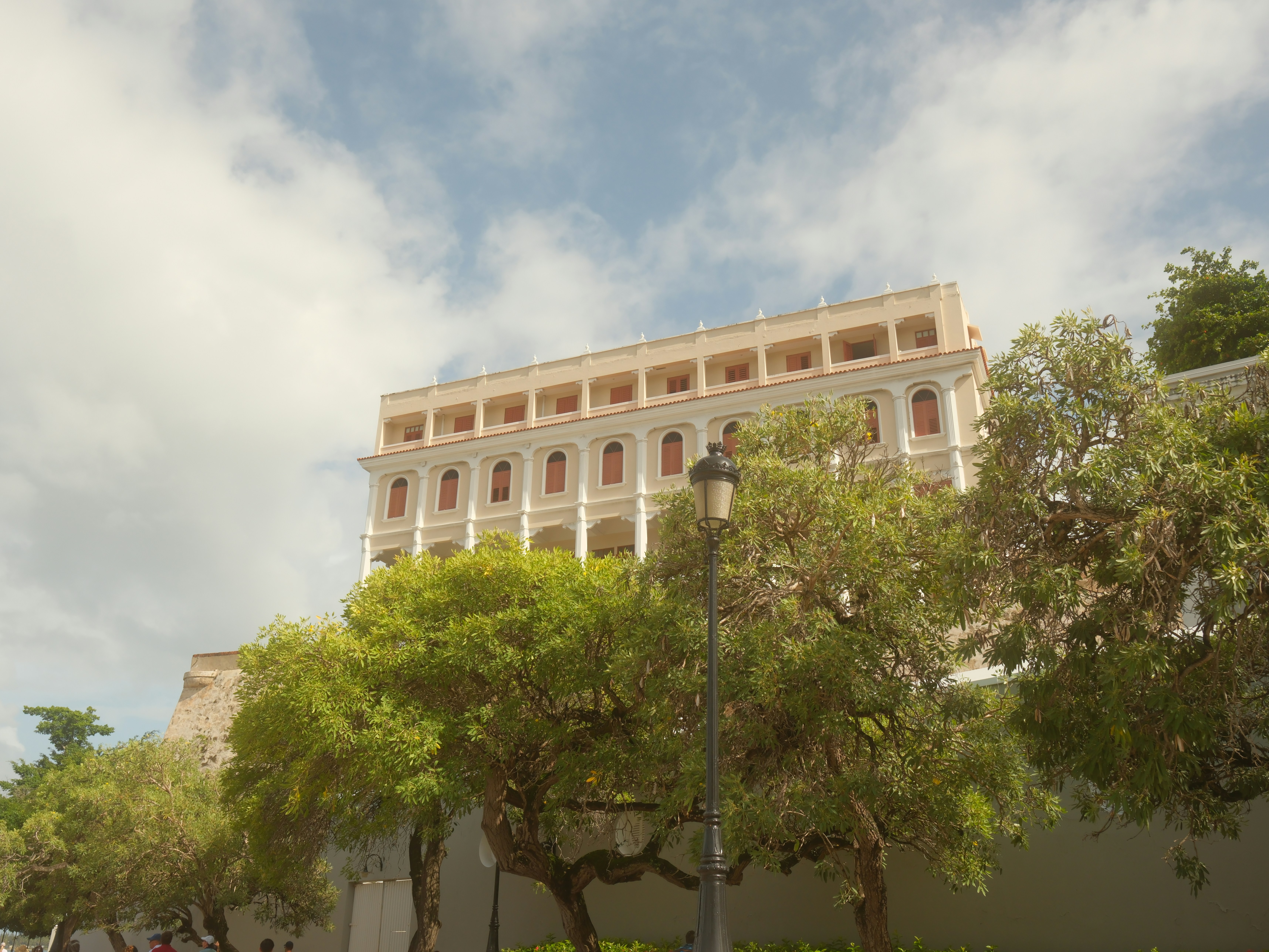 Ornate building behind lush green trees under sky