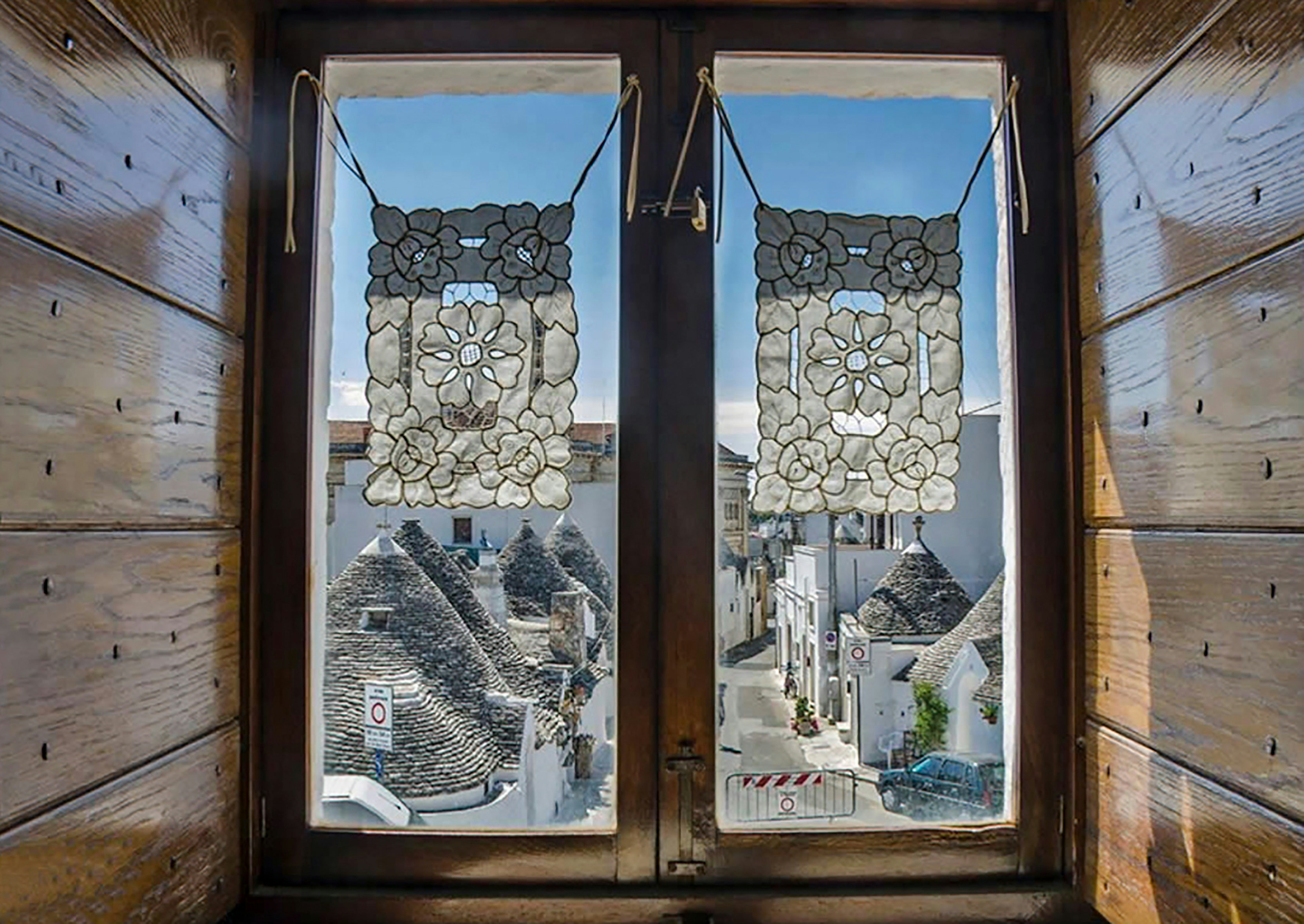 Vista dei trulli di Alberobello attraverso una finestra in legno.