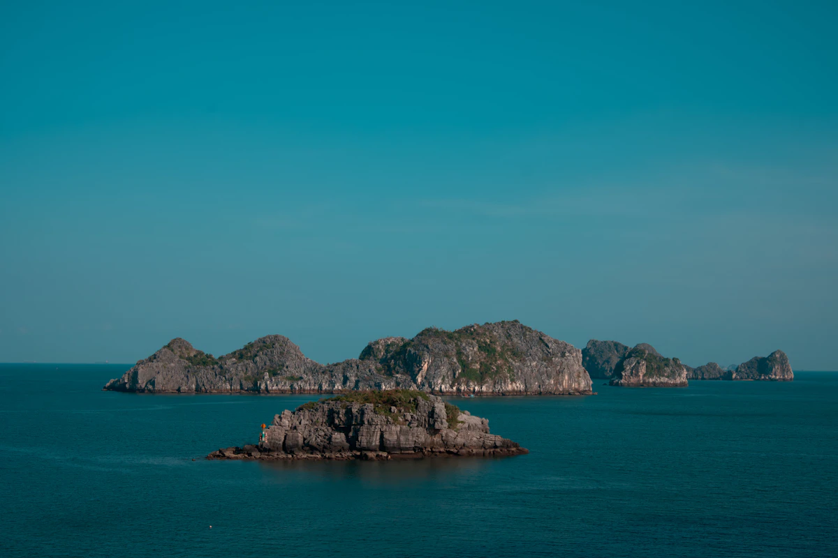 Jagged limestone karst islands rising from the blue water of Ha Long Bay