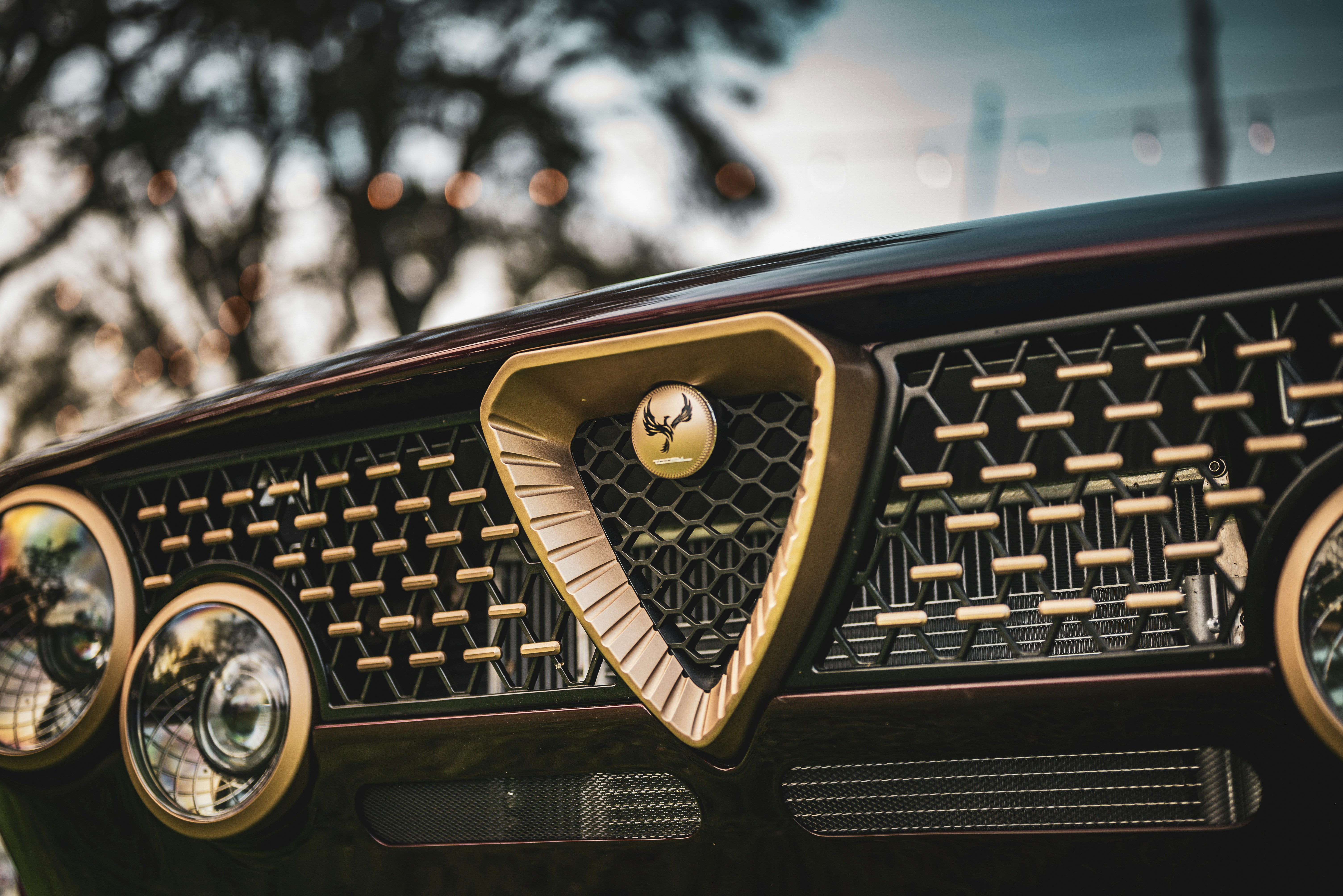 Nahaufnahme des verzierten goldenen Kühlergrills eines Oldtimers.