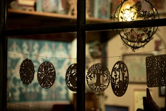 Ornate cutouts hang on a string in a window.