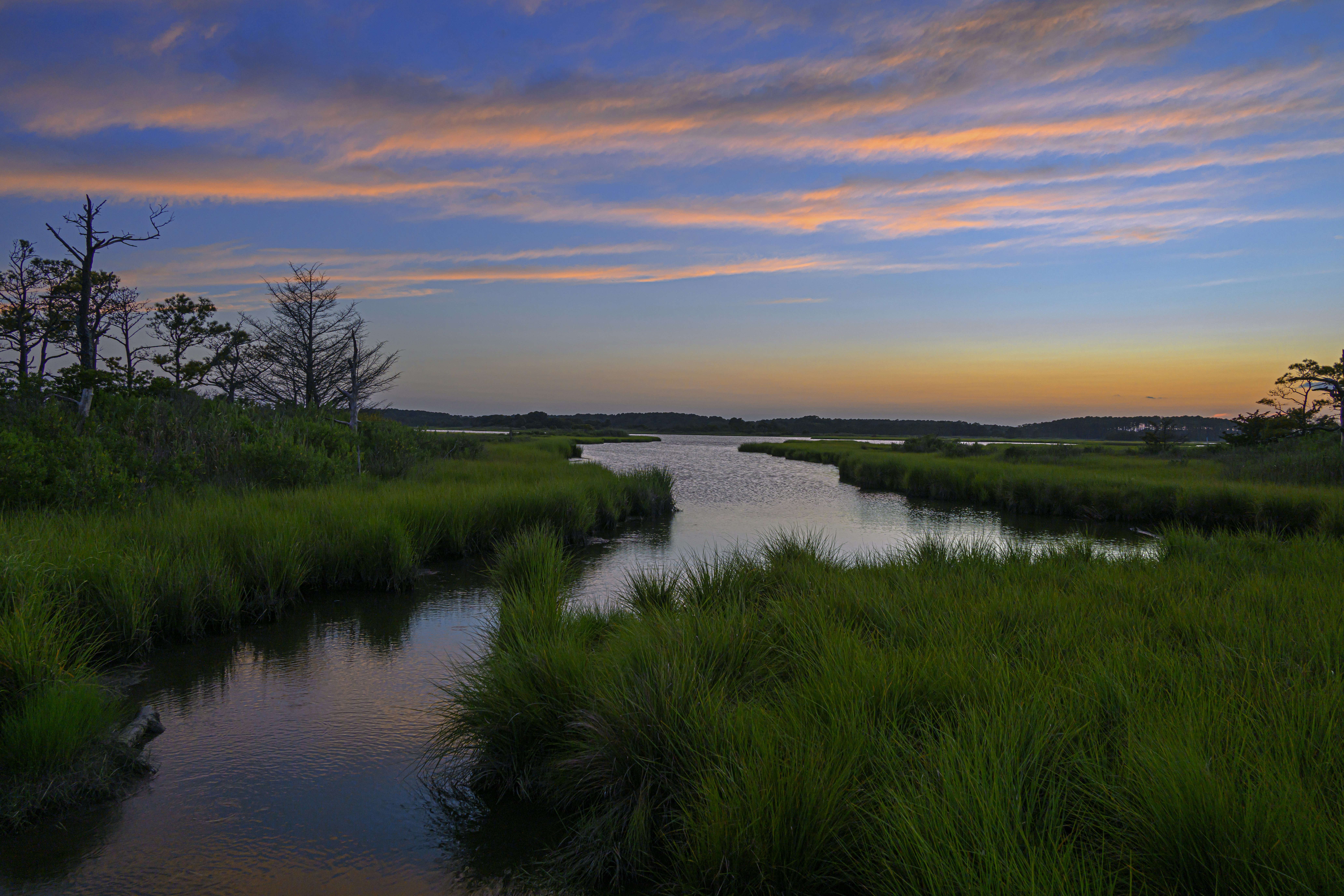 Sunset over a calm river with grassy banks