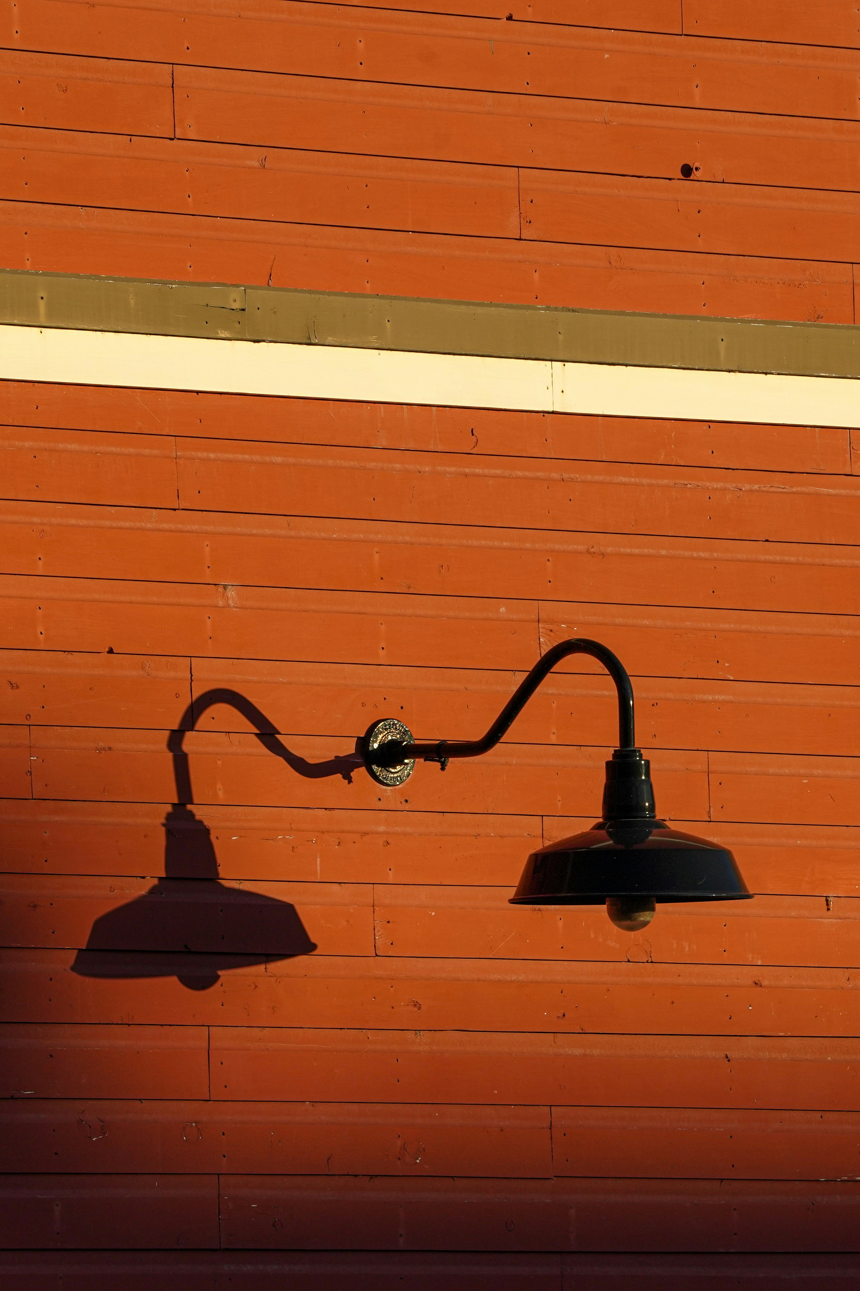 Schwarze Doppel-Scheunenleuchte an roter Wand