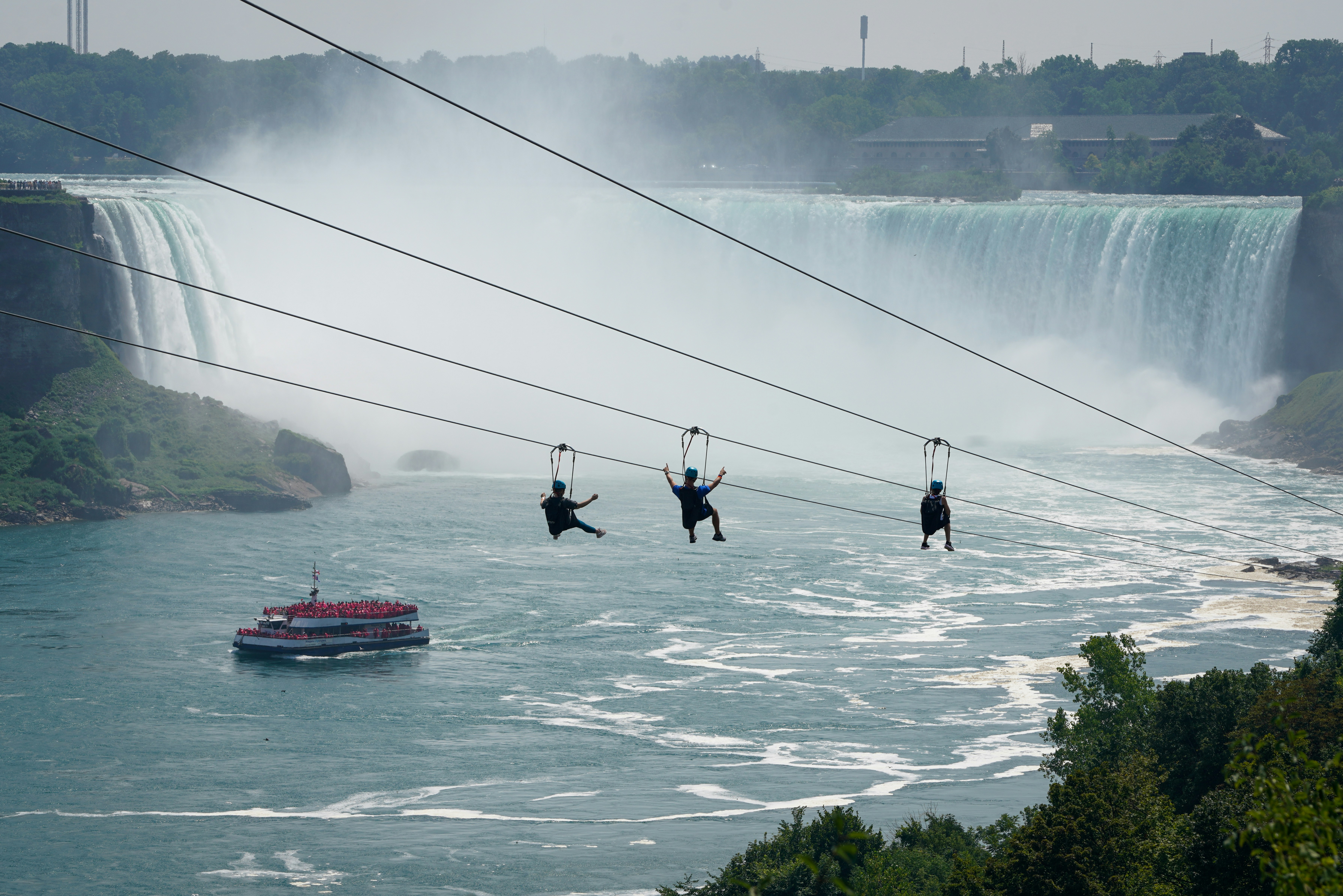 Menschen mit Seilrutsche über die Niagarafälle mit Boot darunter
