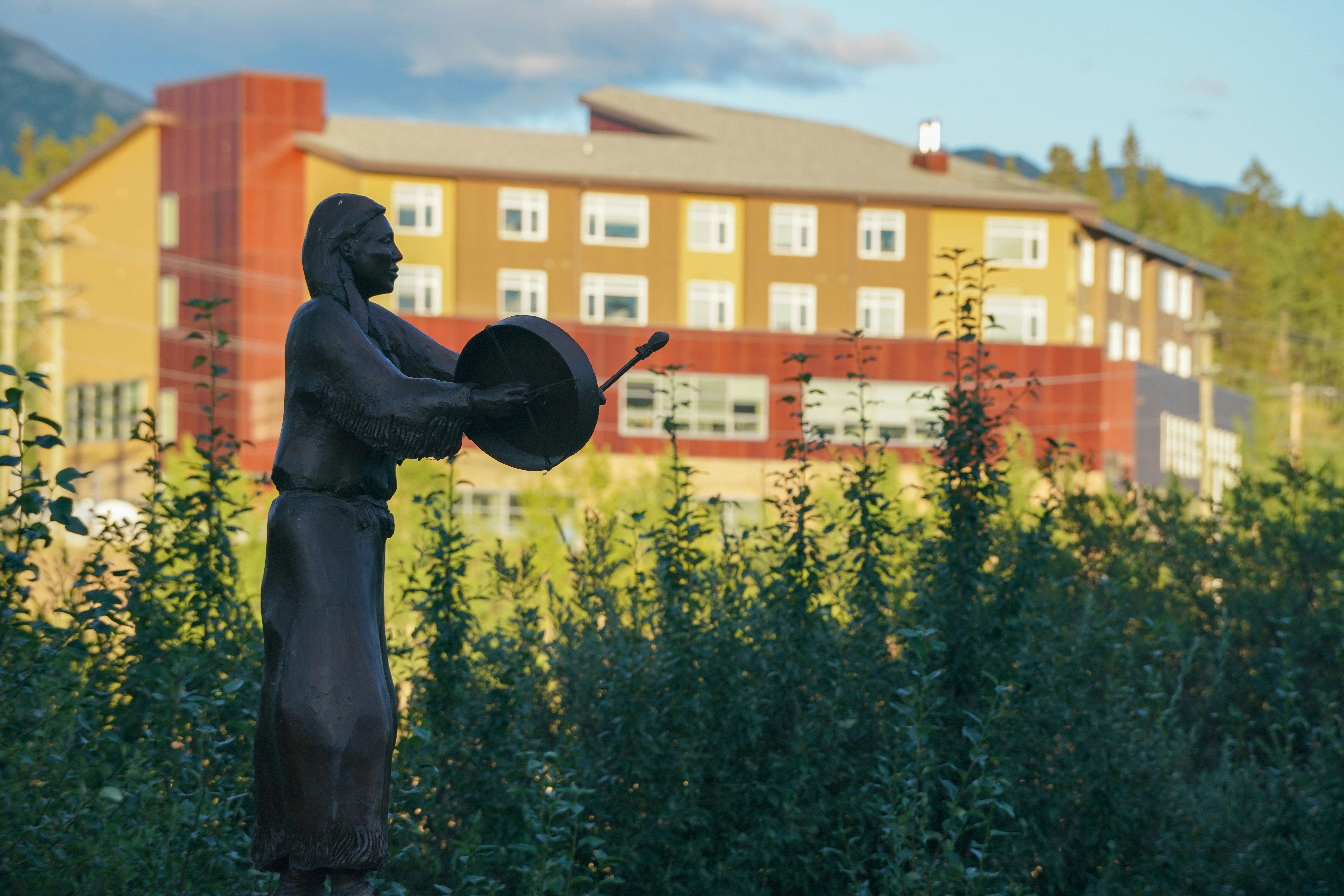 Statue einer indigenen Person, die in der Nähe des Gebäudes Trommel spielt.