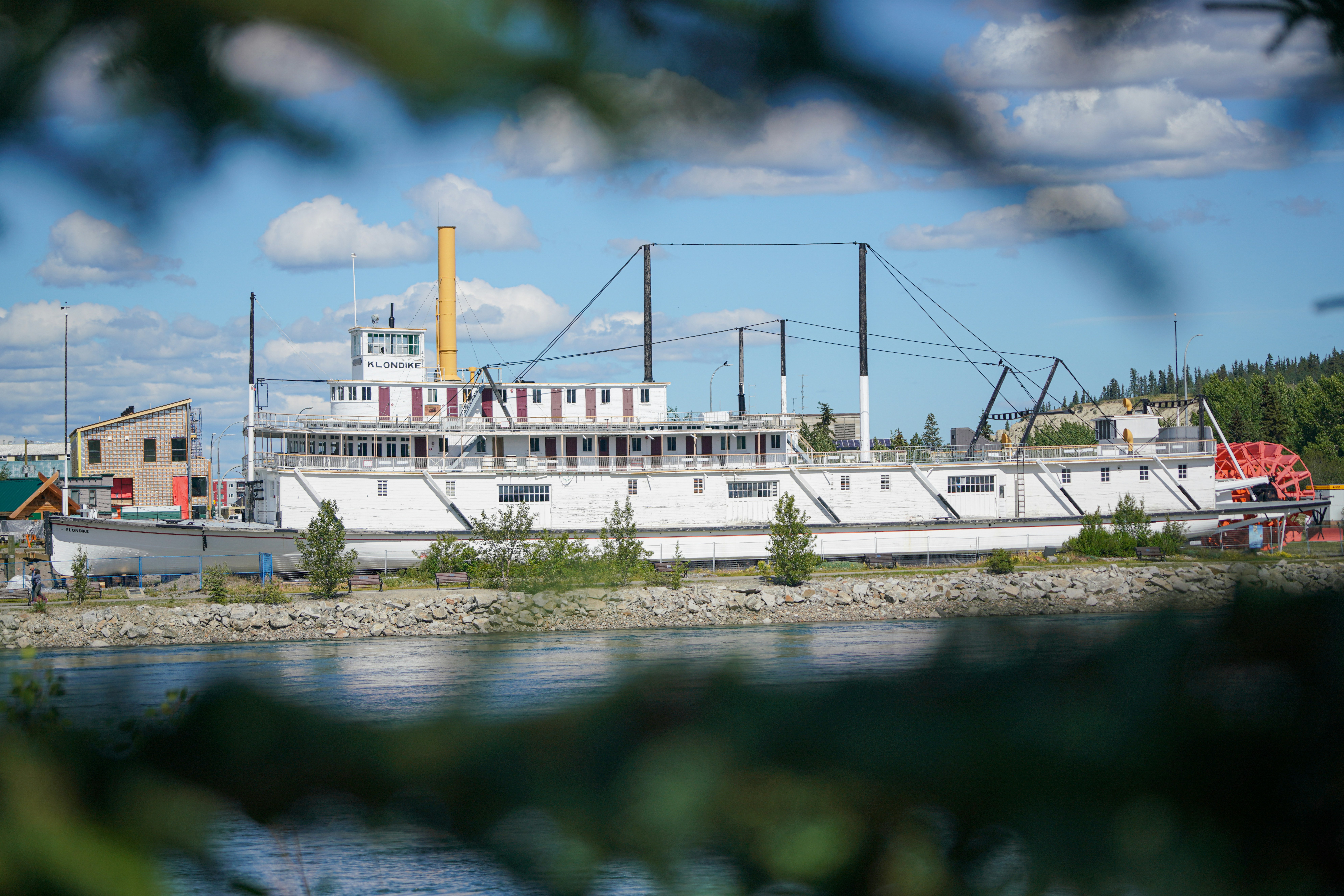 Weißes Schaufelrad-Flussboot, das an einer Küste angedockt ist