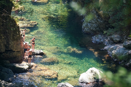 People standing on rocks by a clear river