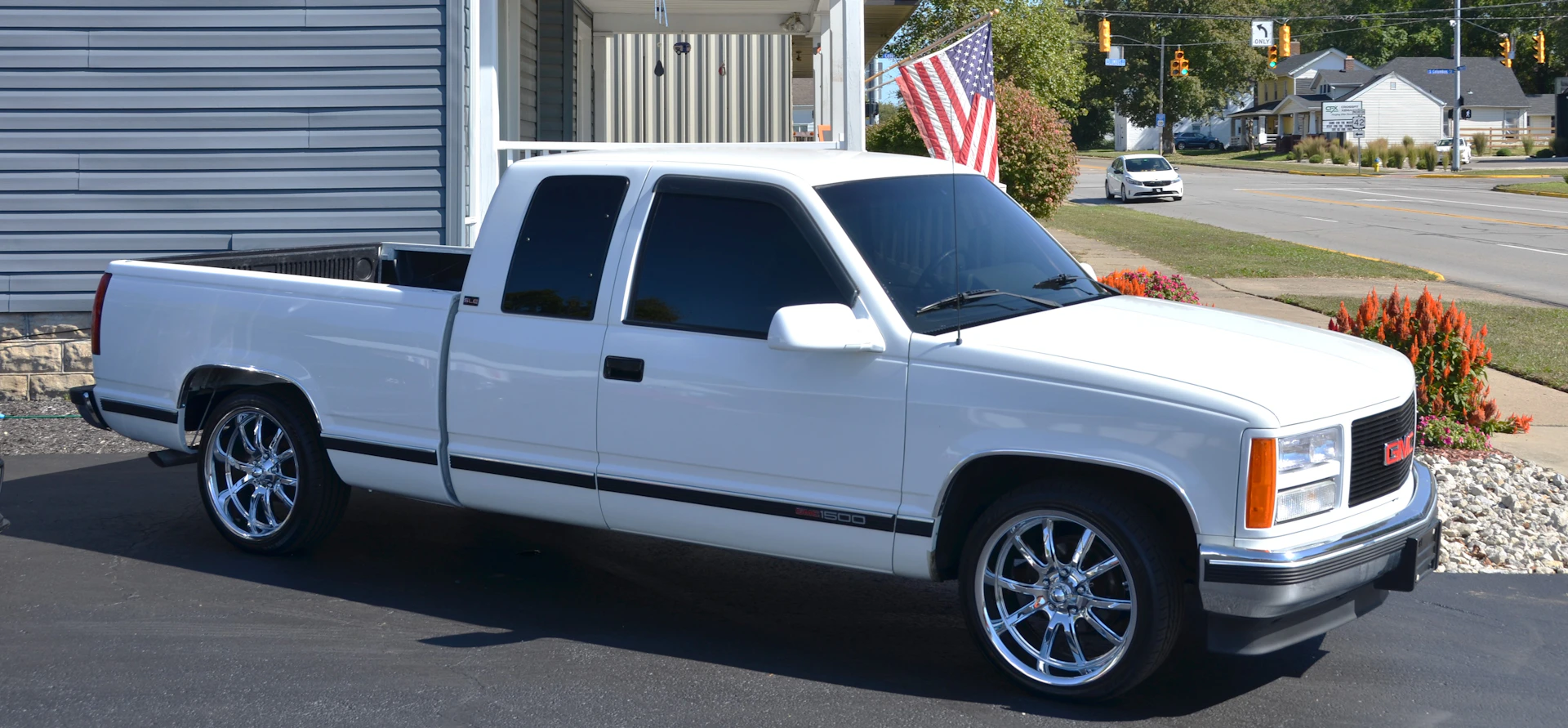 White gmc pickup truck with custom rims parked.