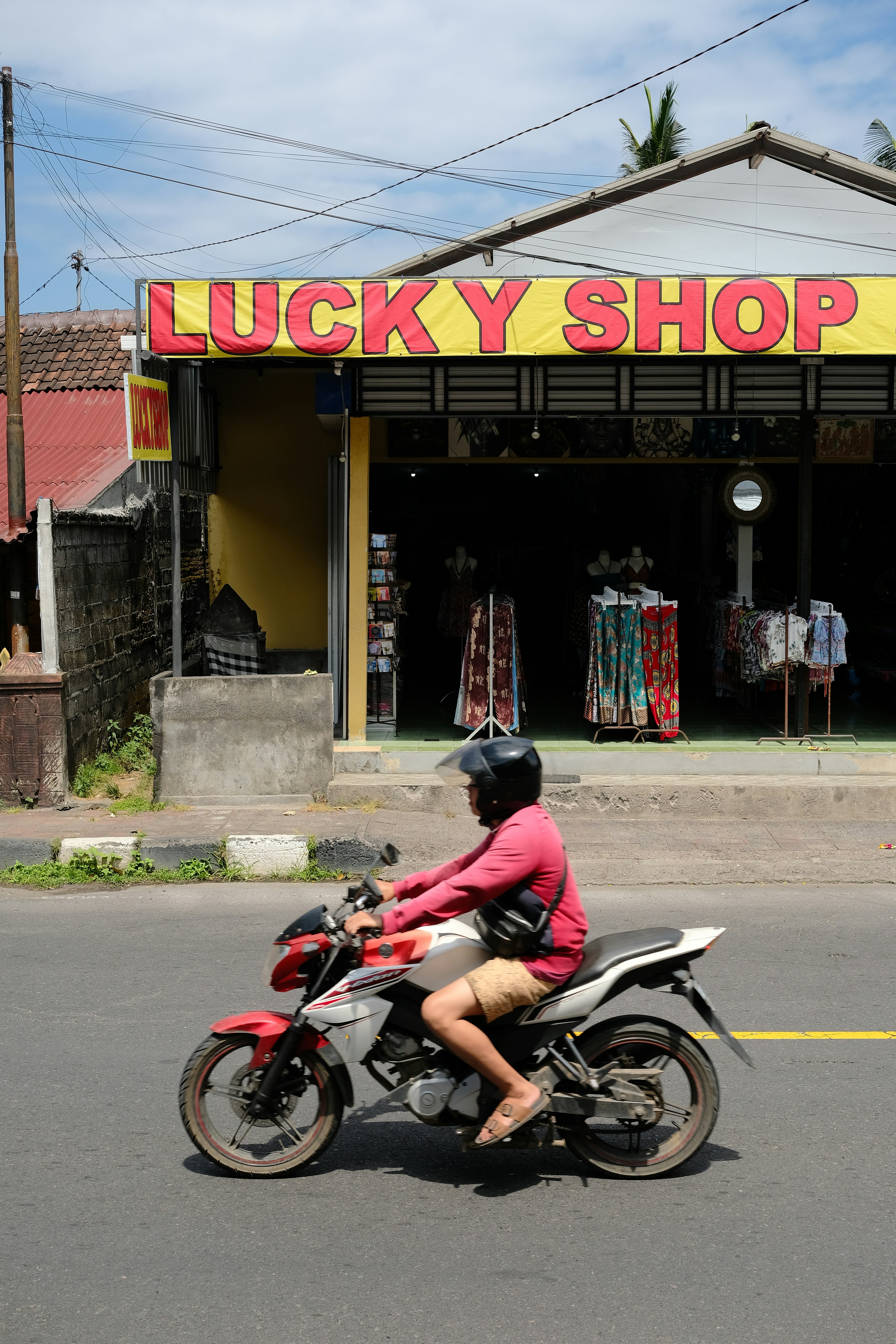Pria mengendarai sepeda motor melewati toko