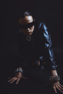 Woman in blindfold and leather outfit on dark background