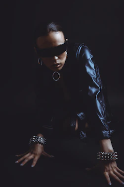 Woman in blindfold and leather outfit on dark background