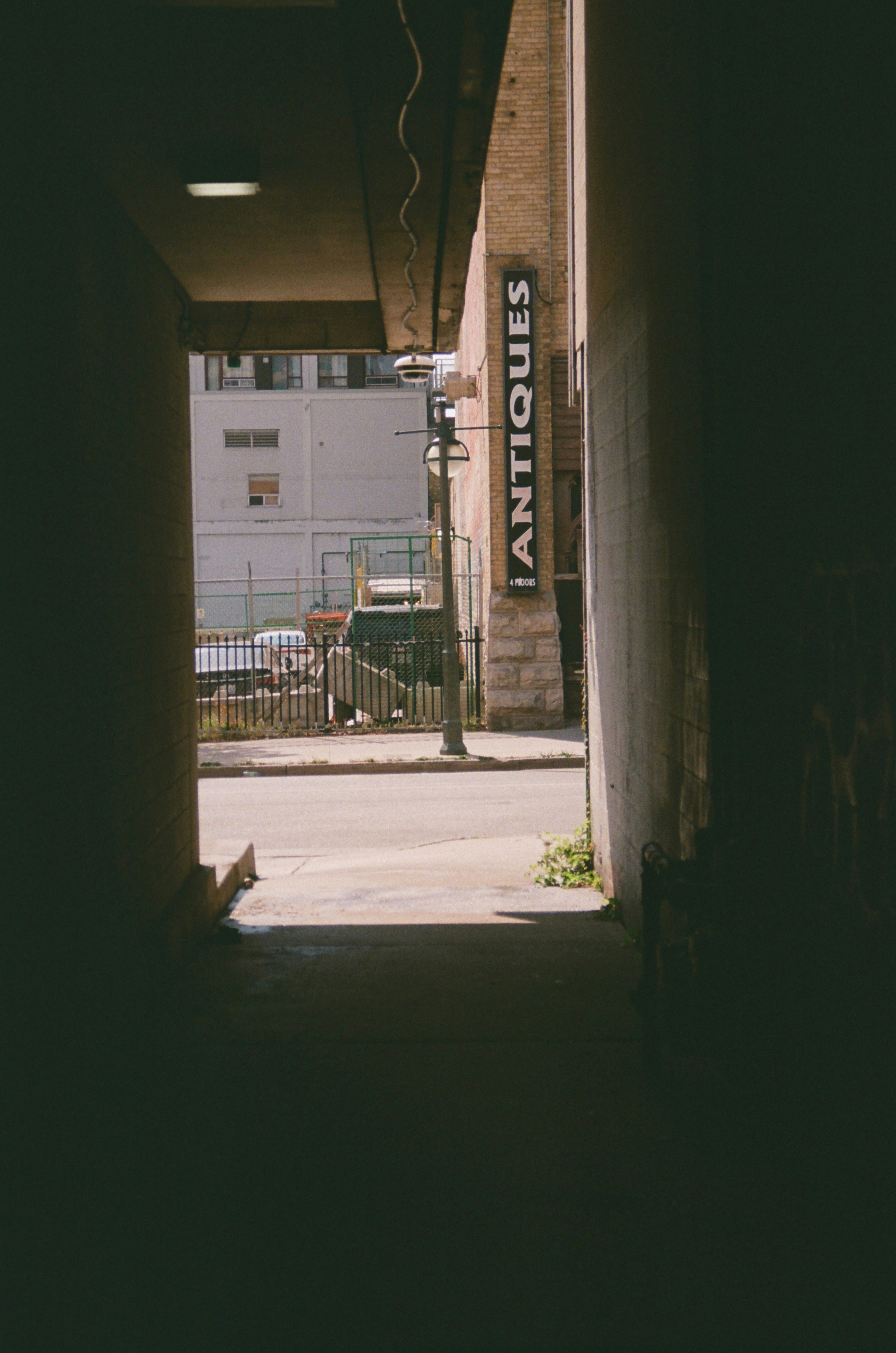 Narrow alleyway opens to street with antiques sign