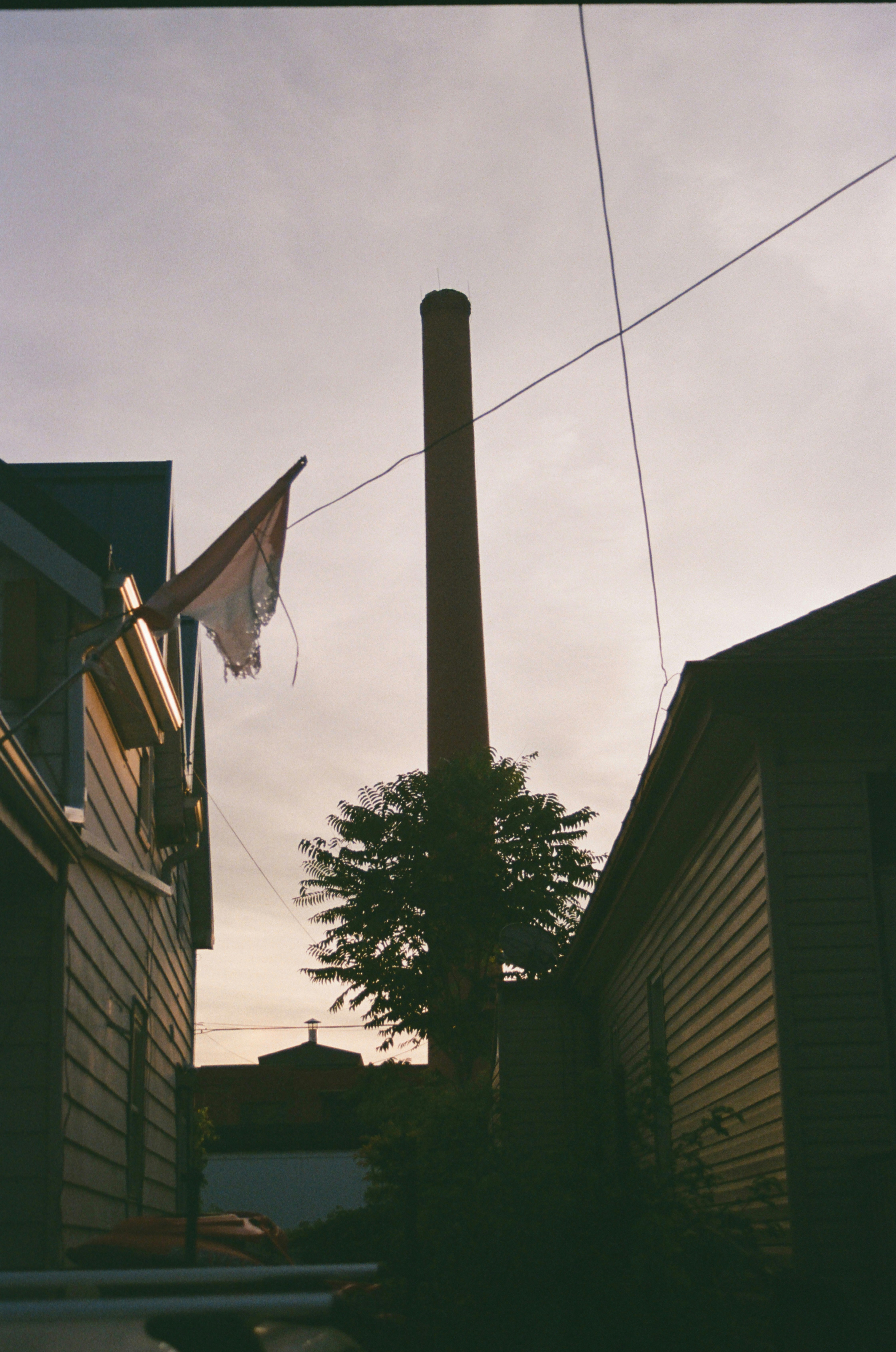 Tall smokestack between two buildings at sunset.