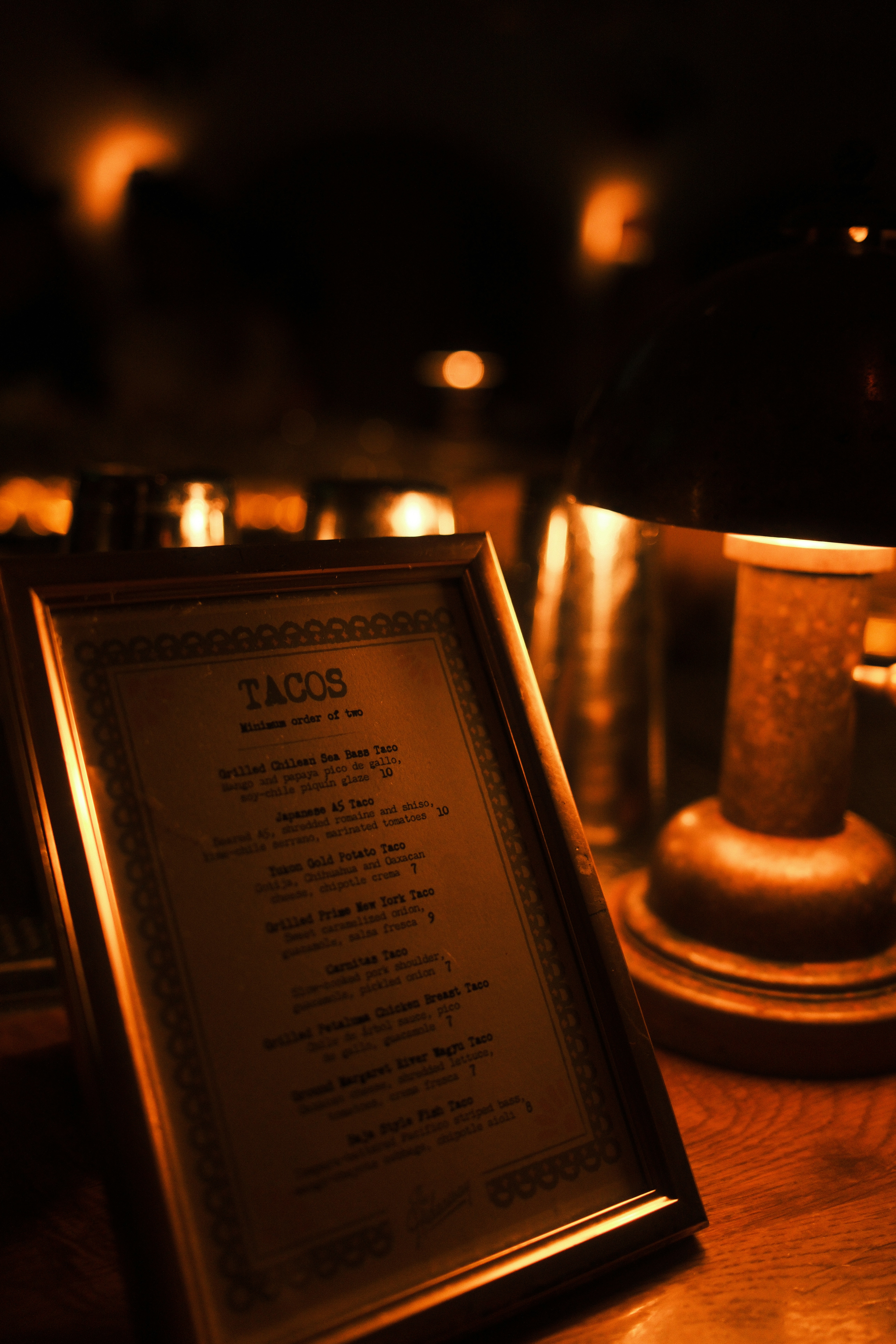Taco menu displayed on a table with lamp.