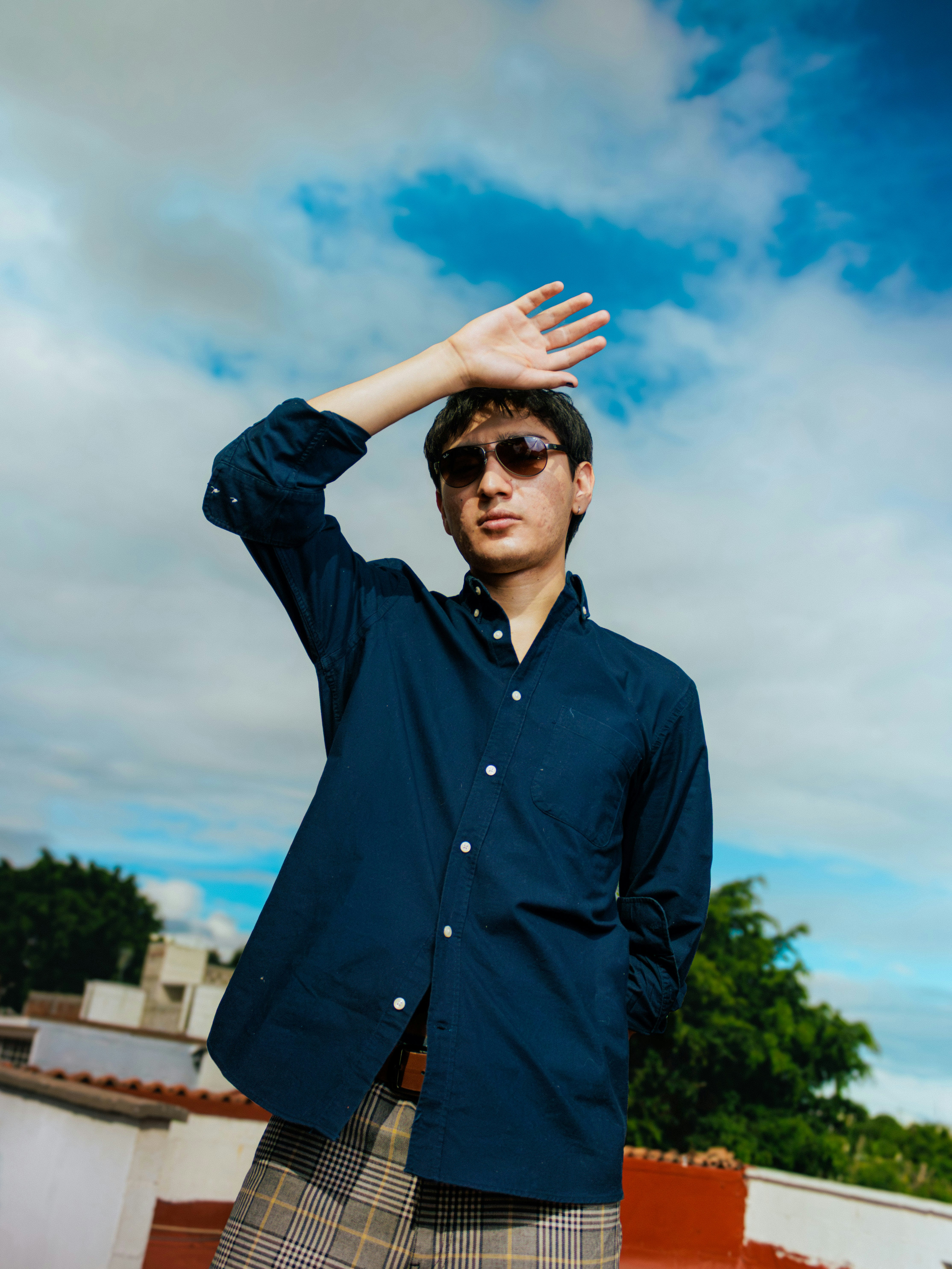 Young man shielding eyes from sun on rooftop