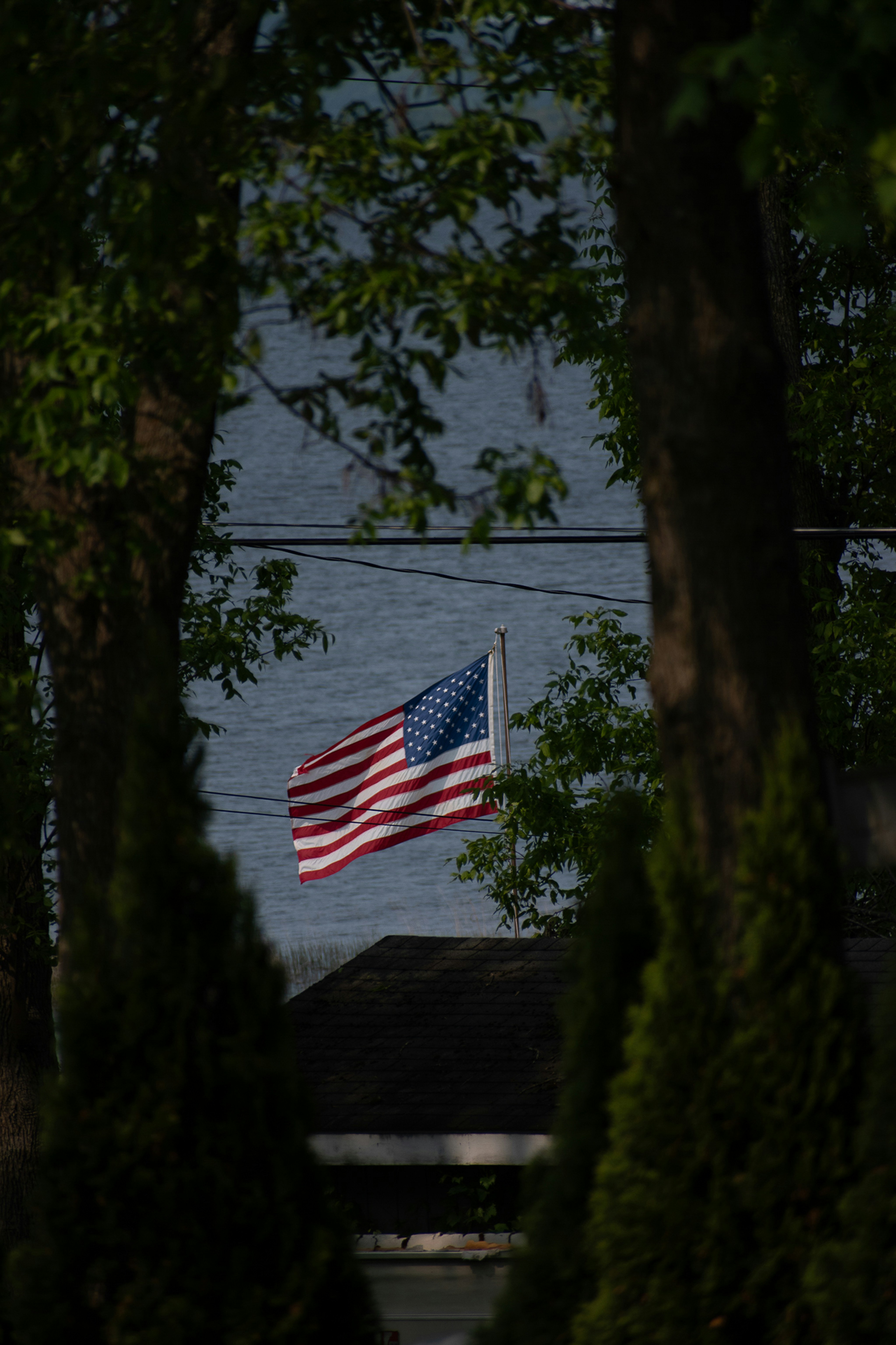 American flag waving over a house by the water
