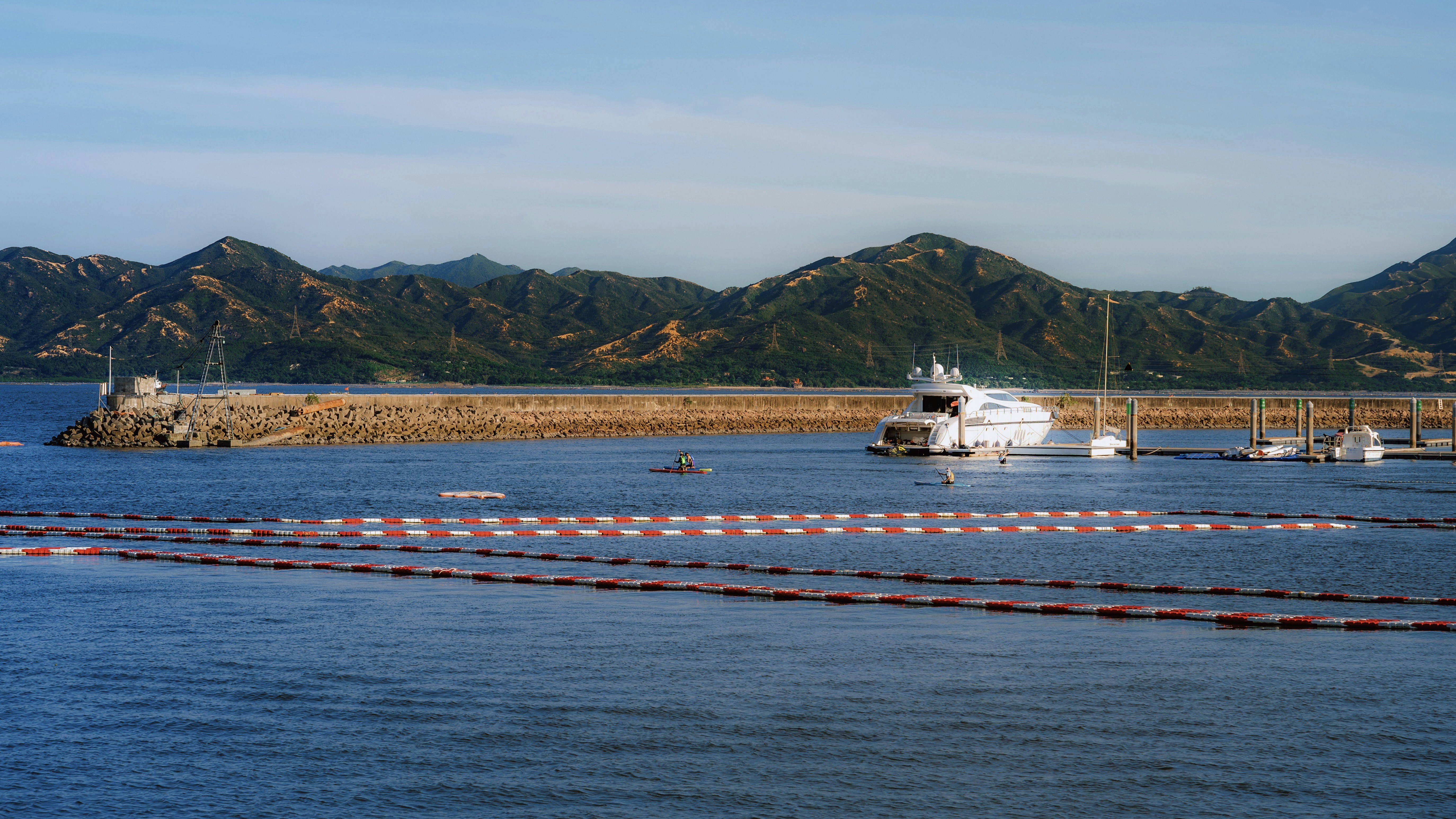 Boats docked in a calm harbor with mountains behind