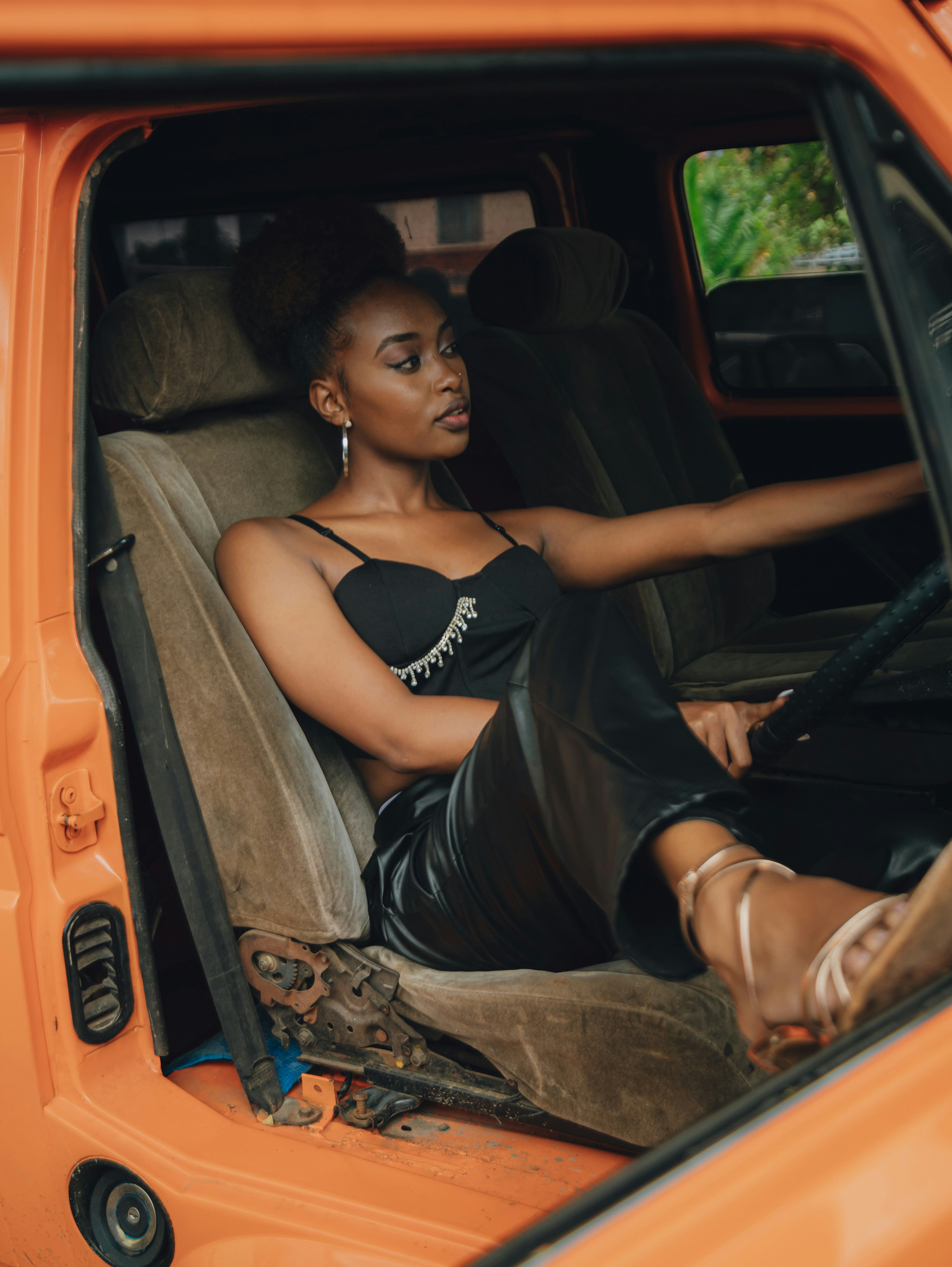 Young black woman sitting in an orange car