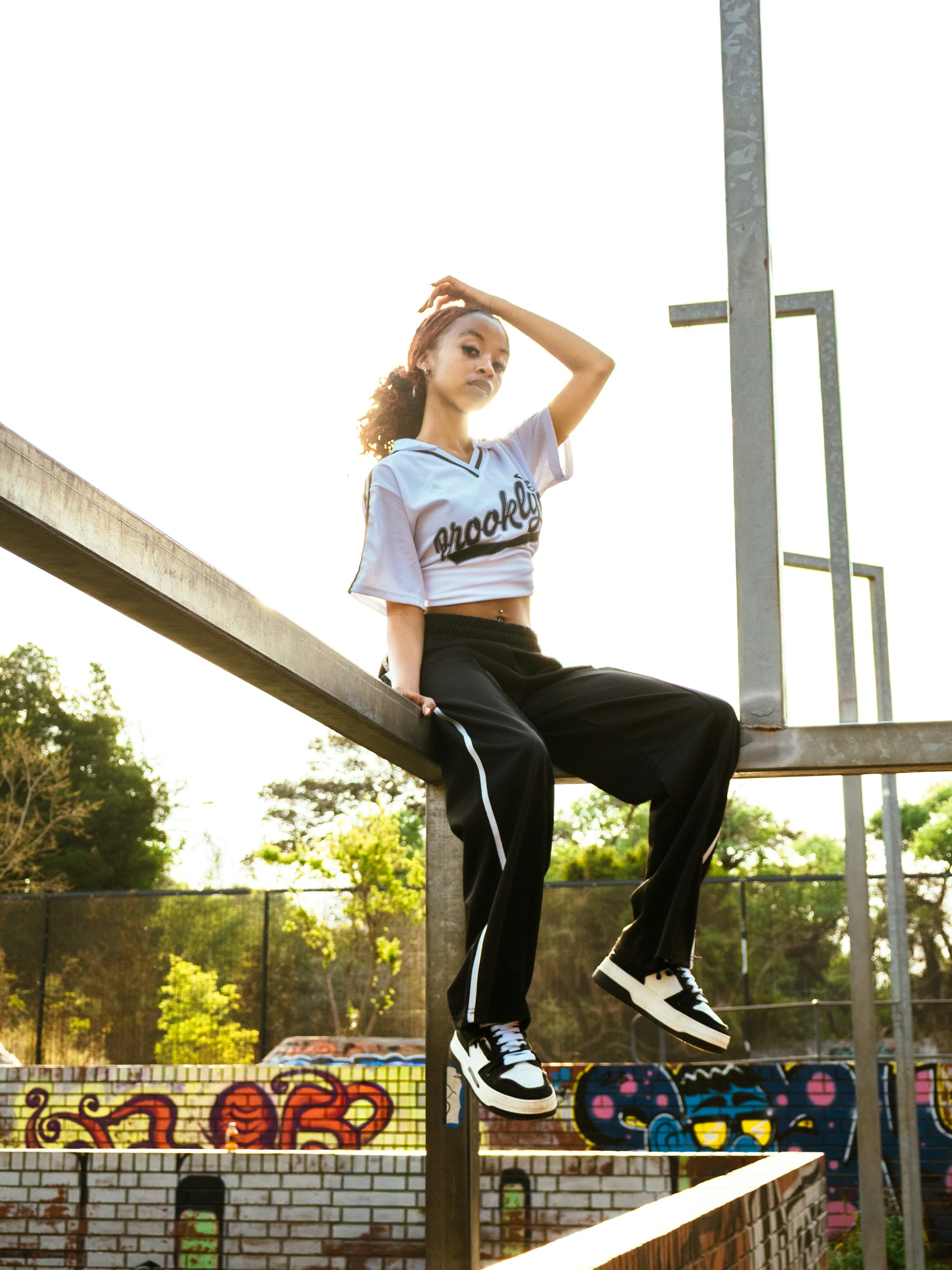 Young woman sitting on urban structure with graffiti background.