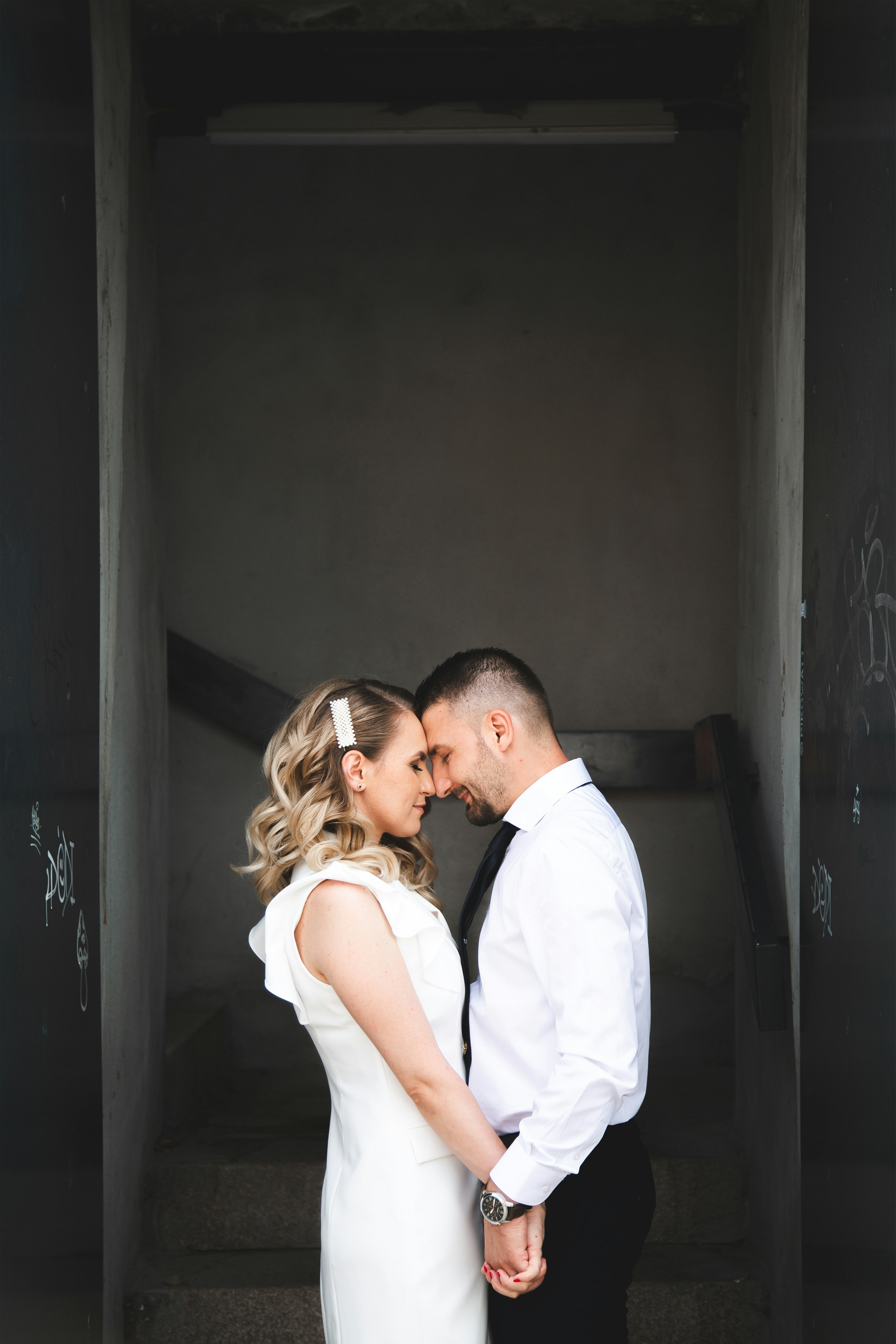 A bride and groom hold hands in a stairwell.
