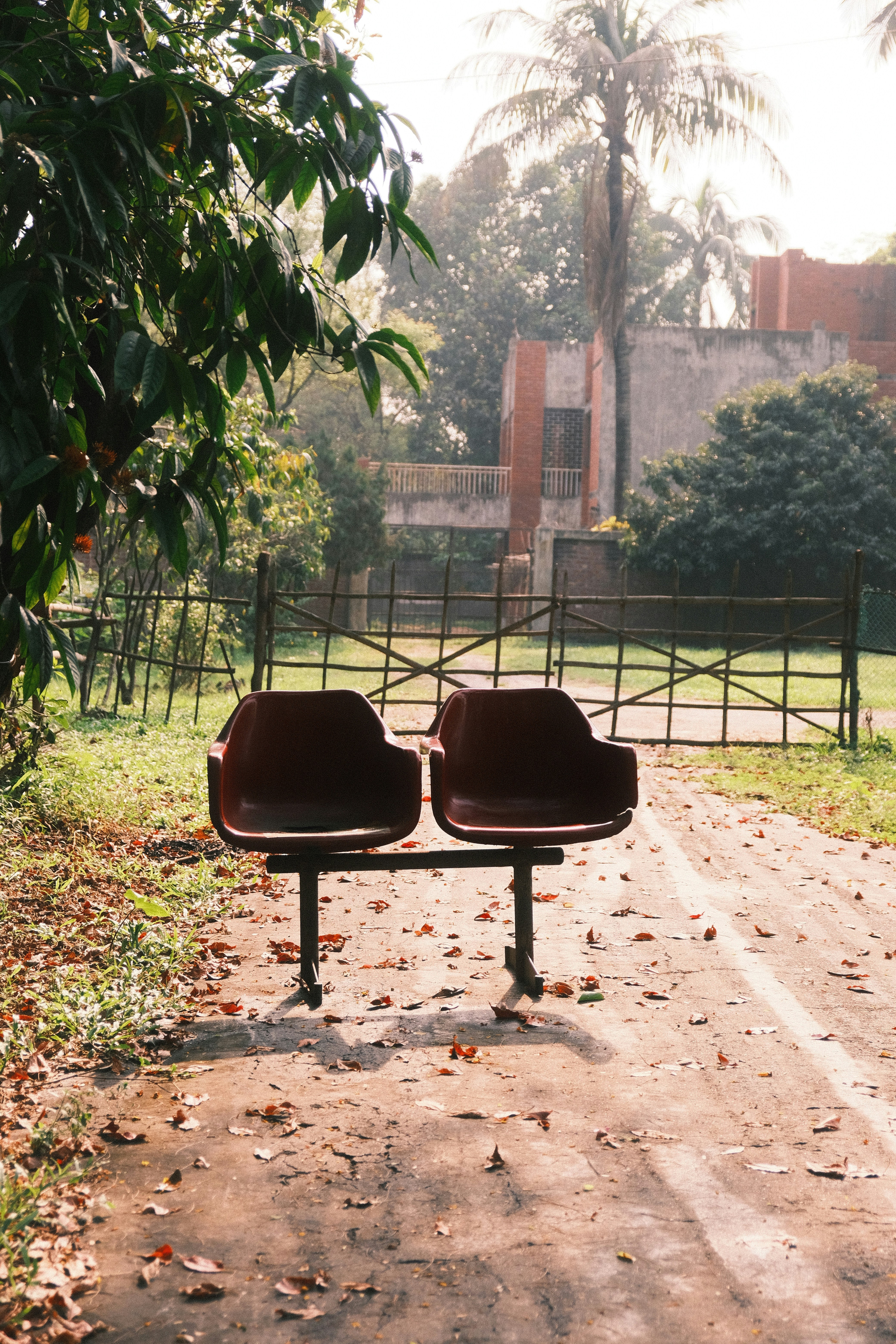 Two empty chairs on a dirt path.