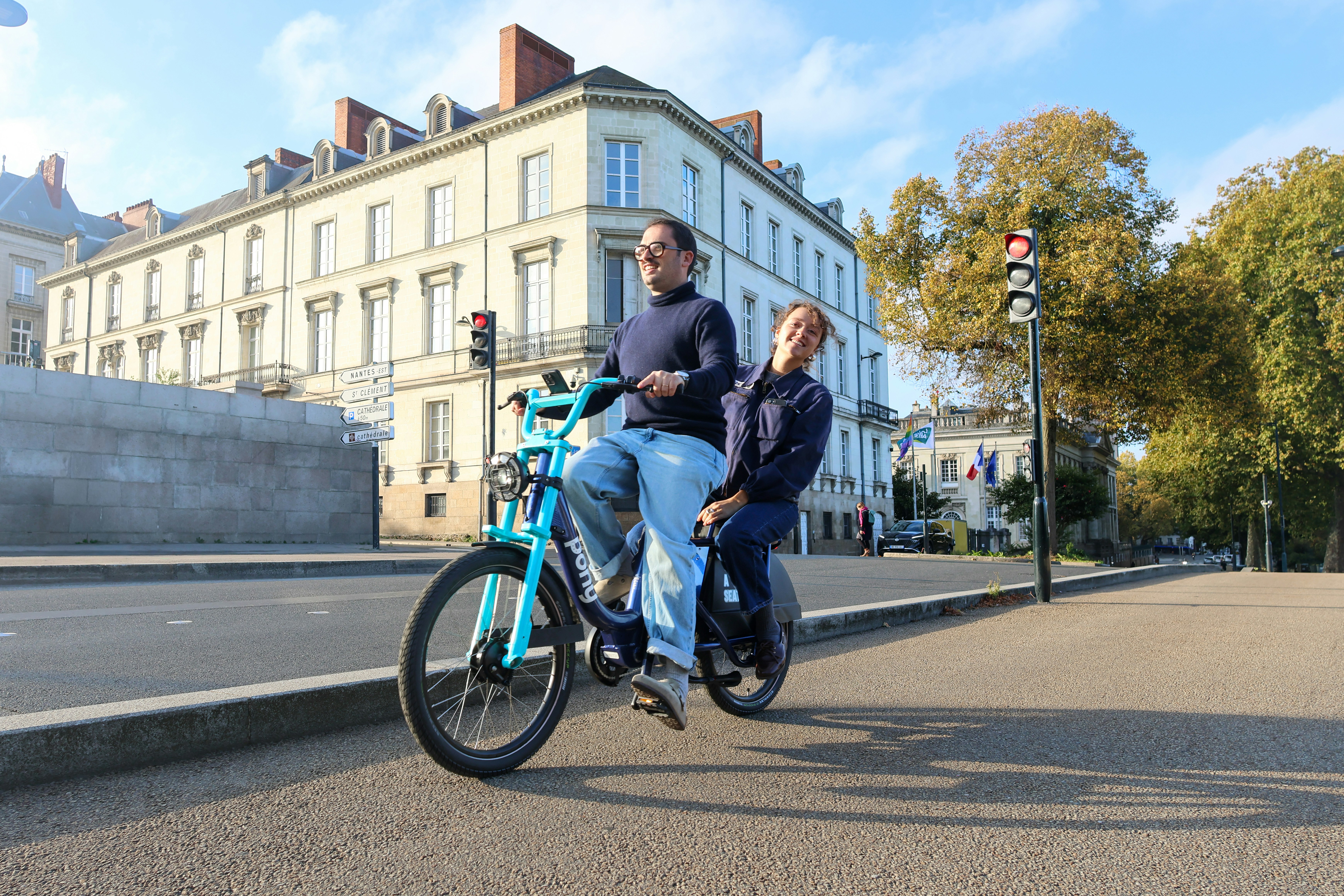 Couple riding a tandem bicycle on a city street
