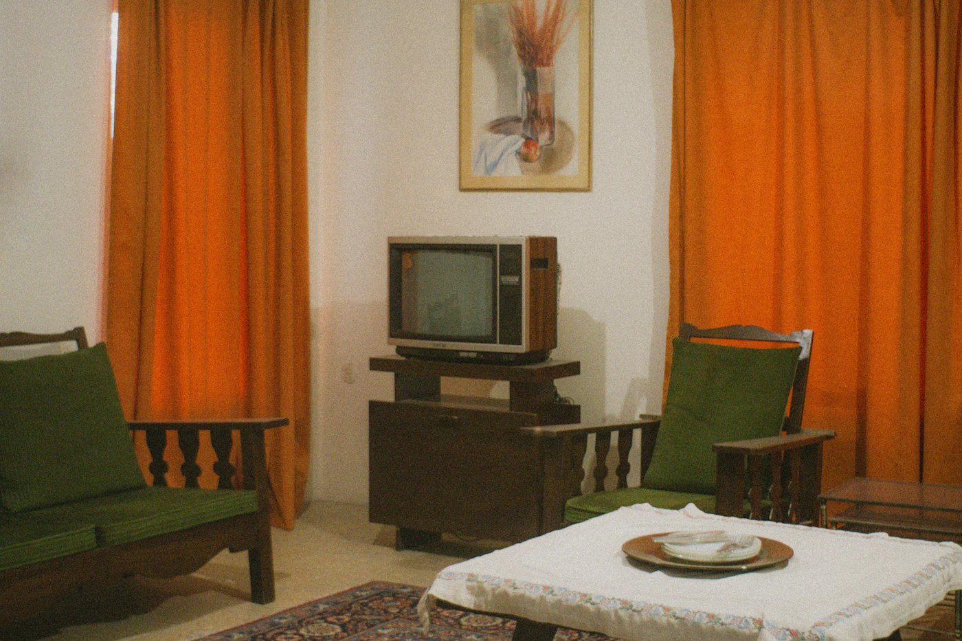 A living room with a vintage television and orange curtains