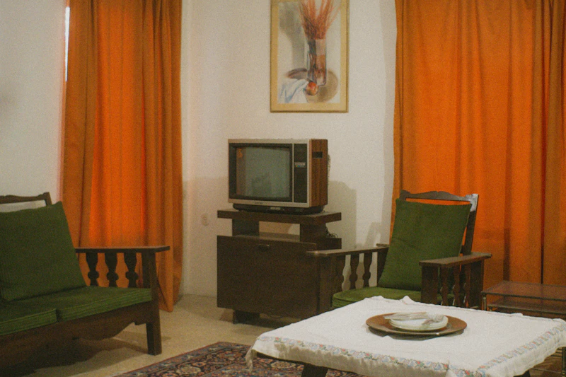 A living room with a vintage television and orange curtains