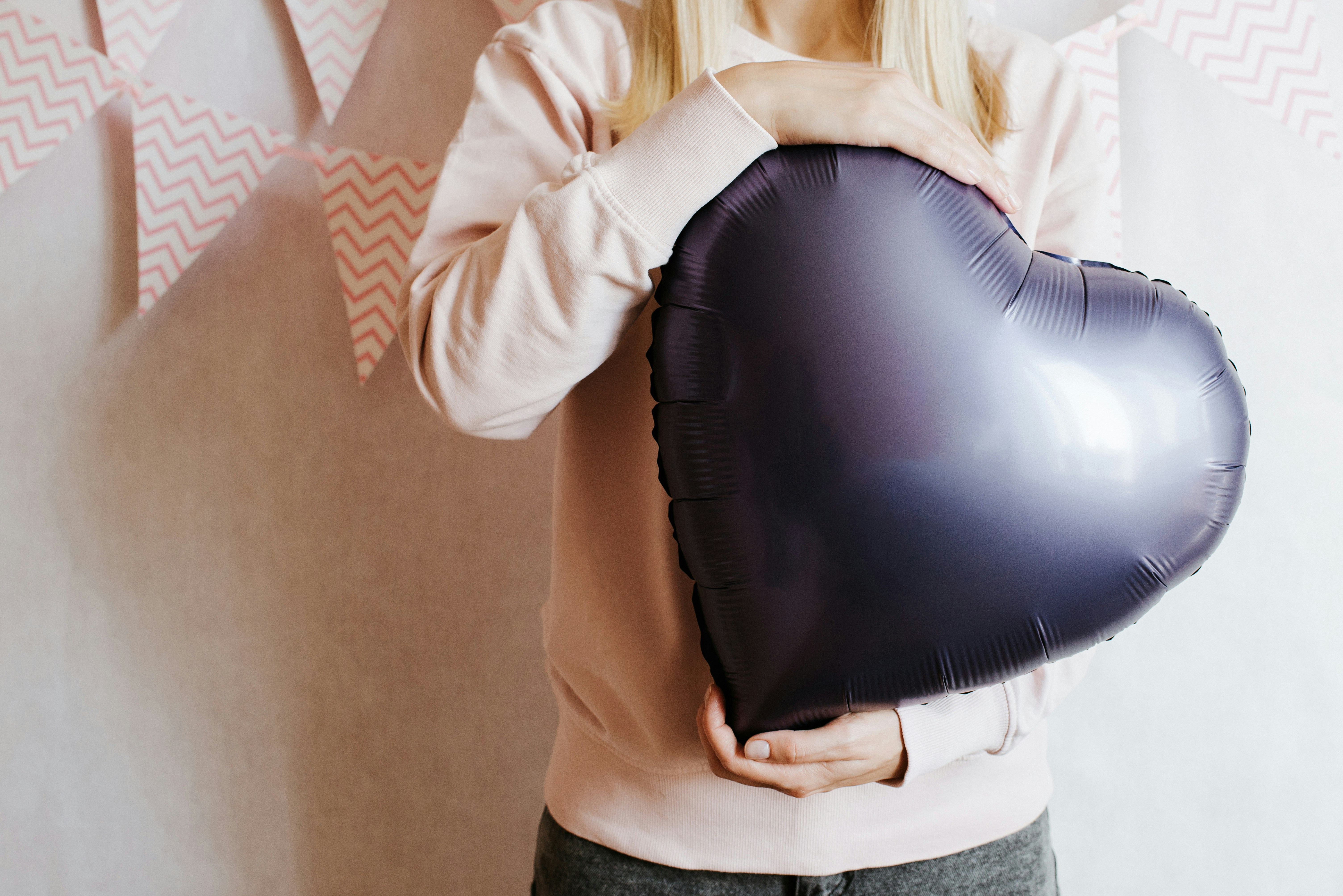 Person holding a dark purple heart-shaped balloon