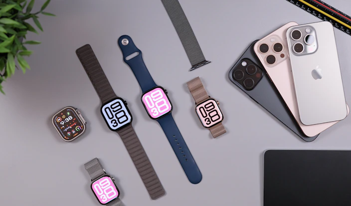 Apple watches and iphones arranged on a desk.