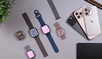 Apple watches and iphones arranged on a desk.