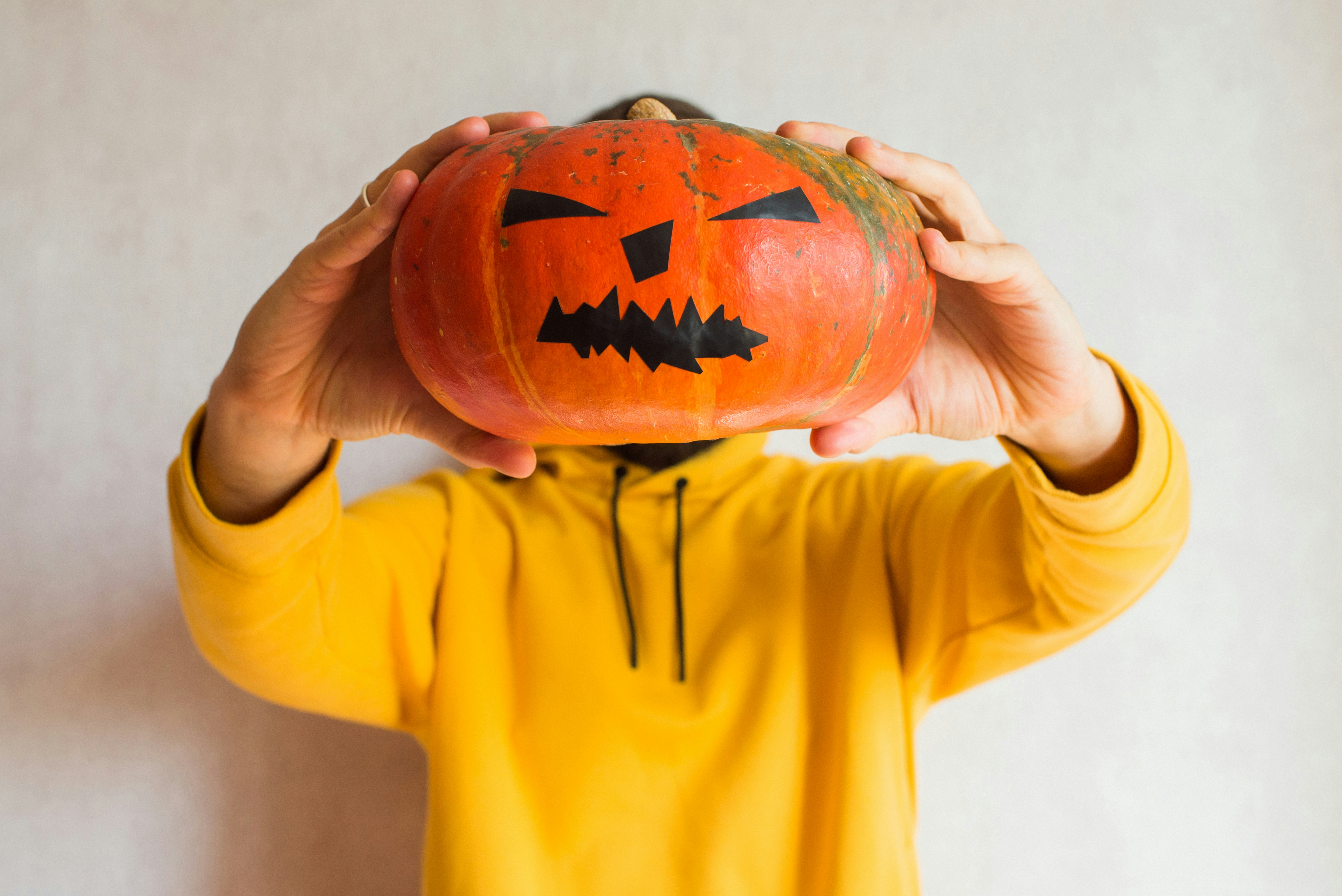 Person holding carved pumpkin over head