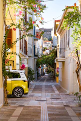 Narrow street with yellow car and blooming flowers