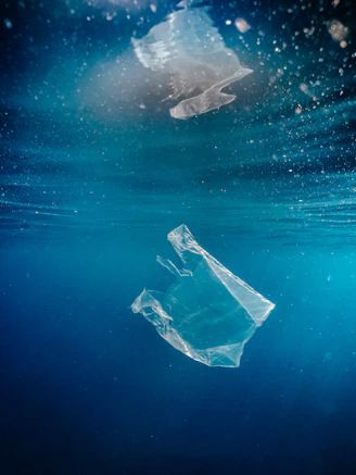 Plastic bag floating underwater in deep blue ocean