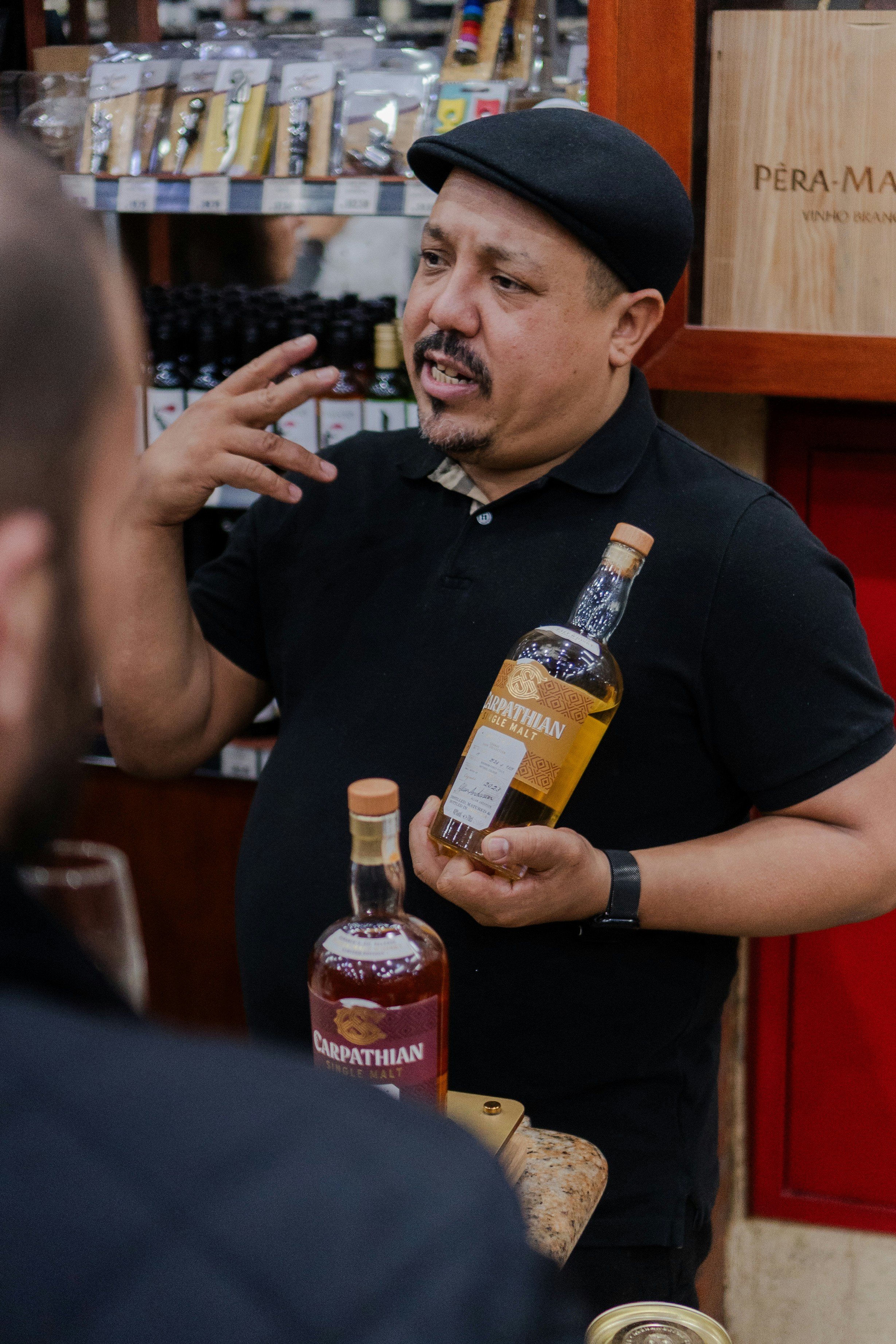 Man holding bottles and gesturing while talking.