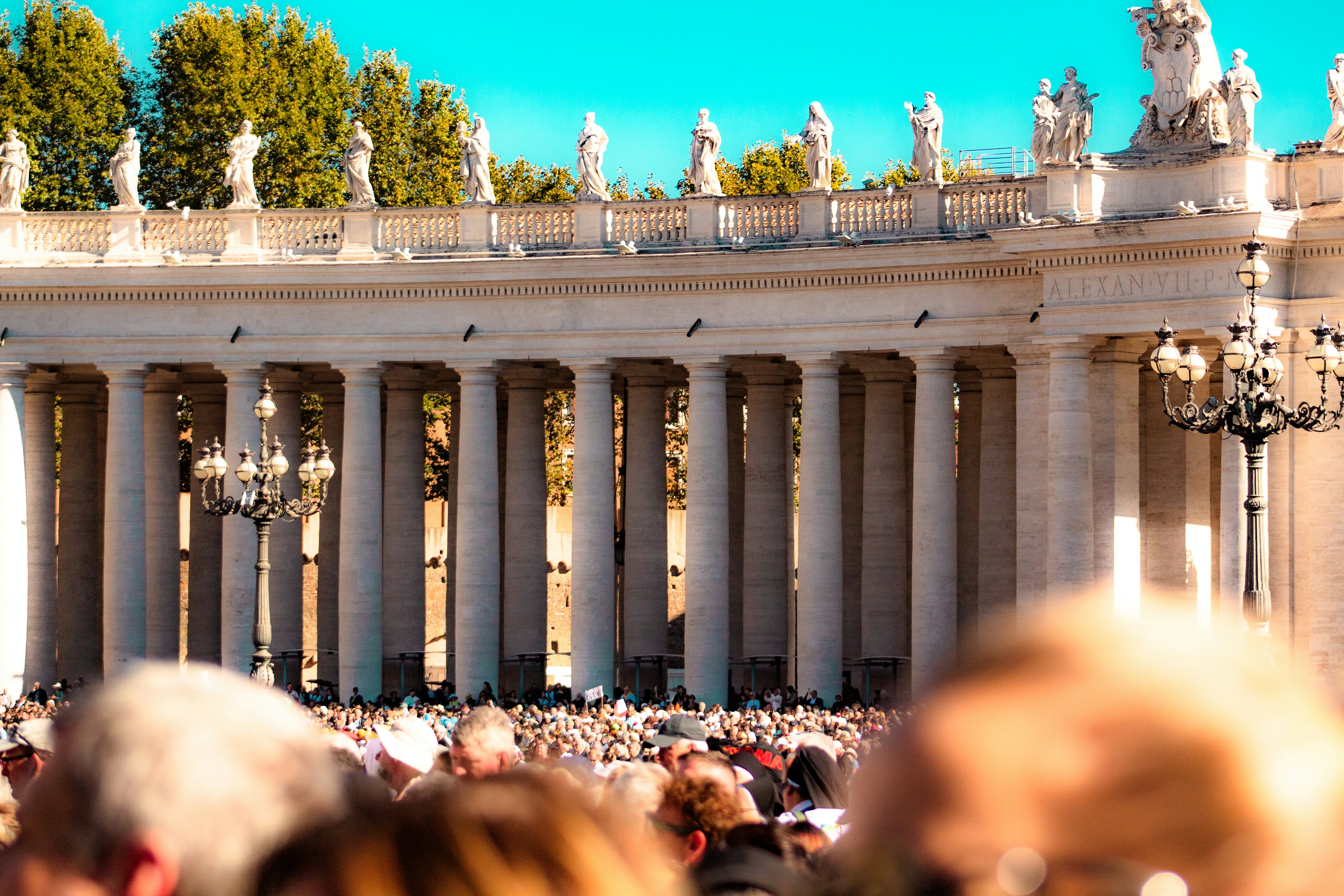 People gathered in a large square with colonnades.