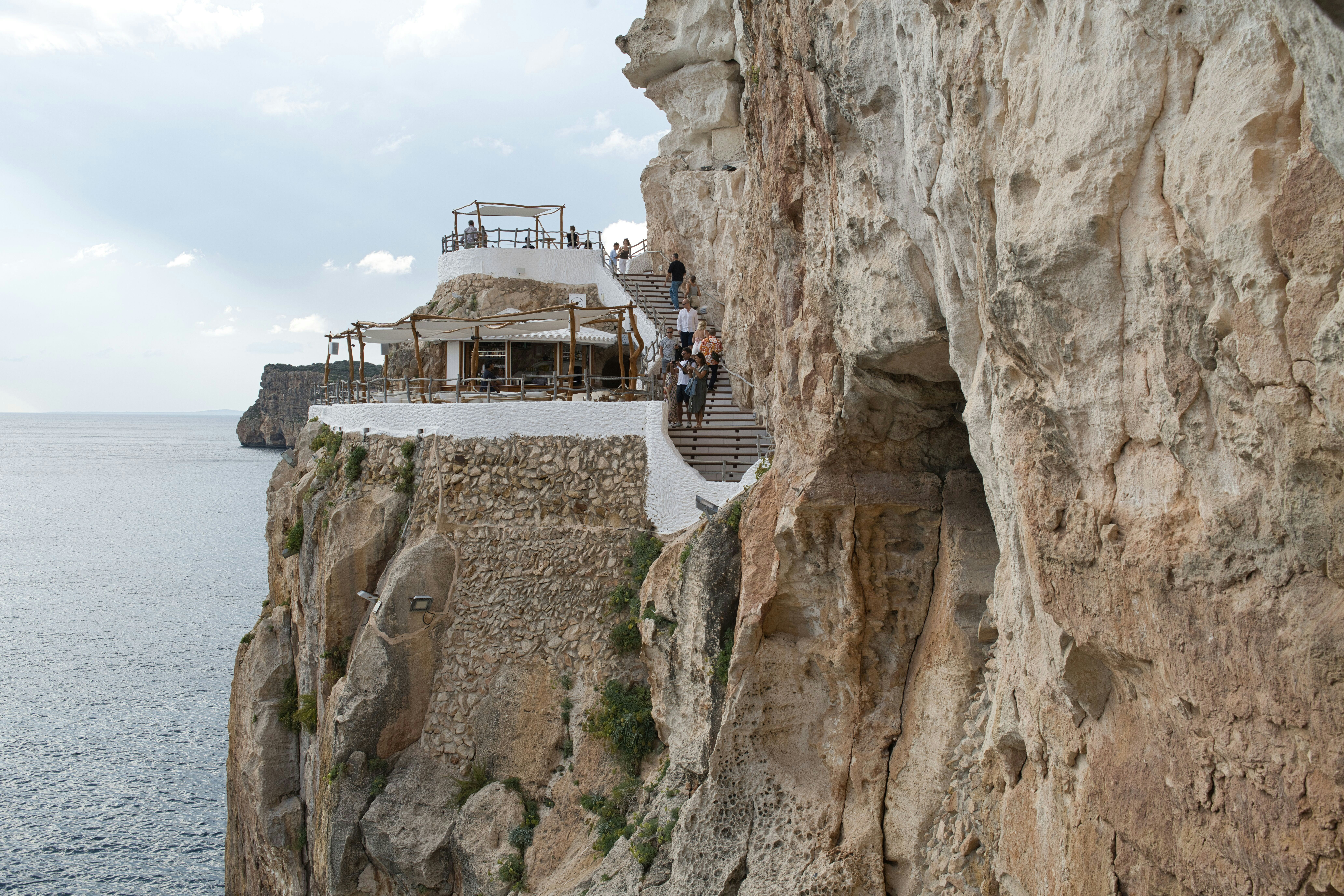 Cliffside restaurant overlooking the ocean with people walking path