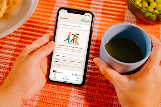 Hands holding smartphone with app, coffee cup, and food.