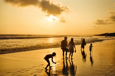 Family walking on beach at sunset