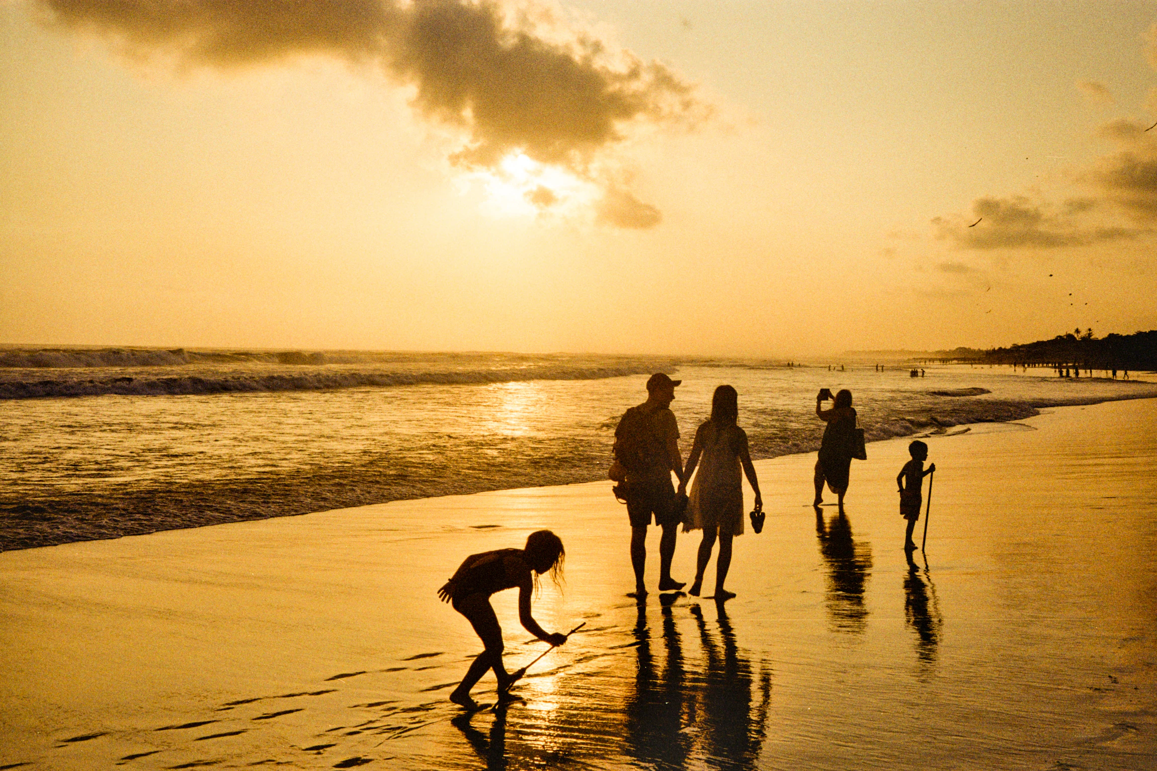 Family walking along the beach in the golden light of sunset