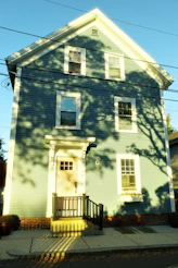 A light blue house with shadows from trees.