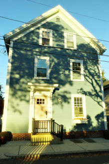 A light blue house with shadows from trees.